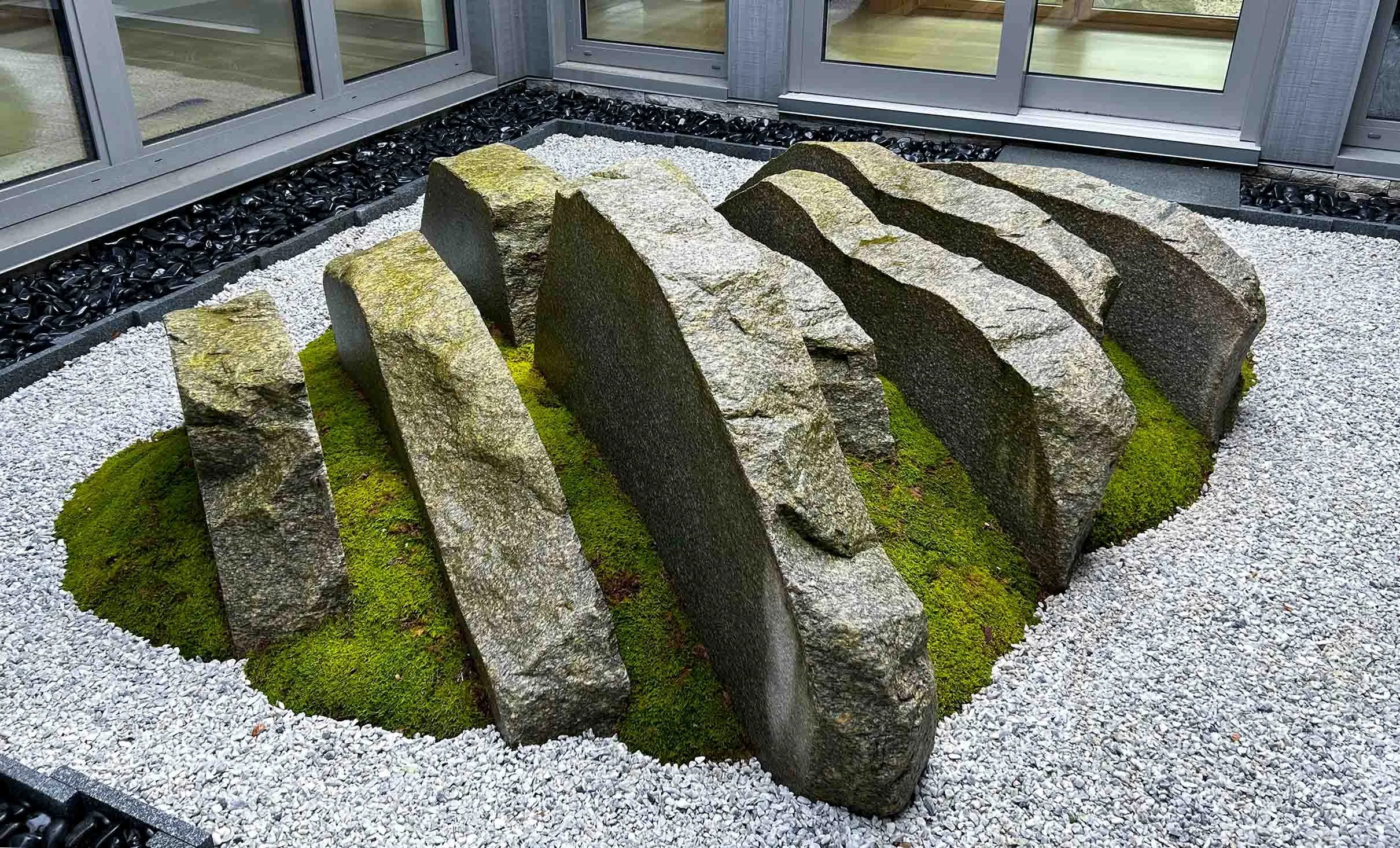 Modern Japanese courtyard atrium garden with cut granite pieces and moss