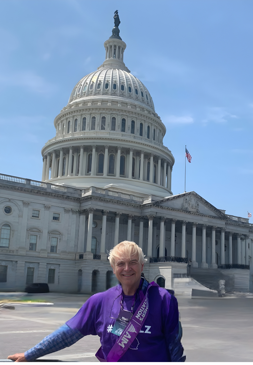 A smiling woman with blonde hair standing in front of the United States Capitol building in Washington, D.C., with the dome and American flag visible in the background.