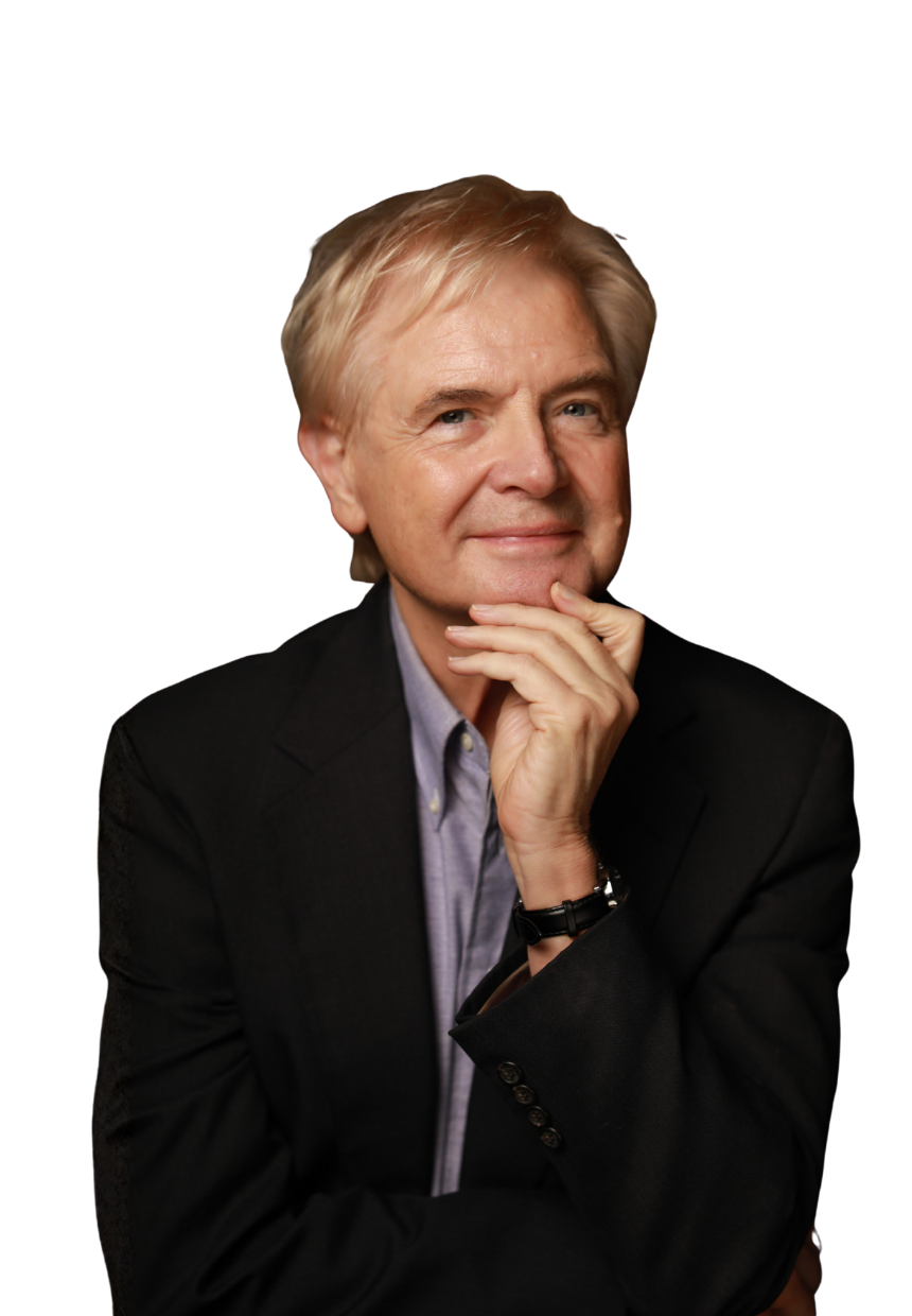 A middle-aged man with blond hair, dressed in a black blazer and light-colored shirt, posing with his hand on his chin and smiling softly.