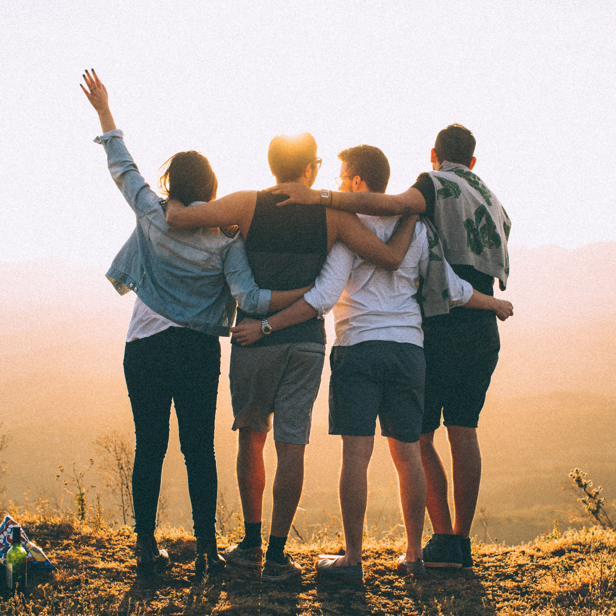 A group of friends stands with their arms around one another's backs in unity