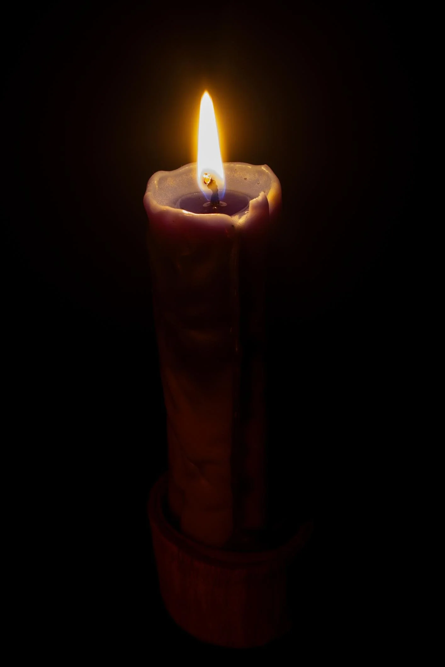 Une bougie allumée dans l'obscurité, avec une flamme lumineuse