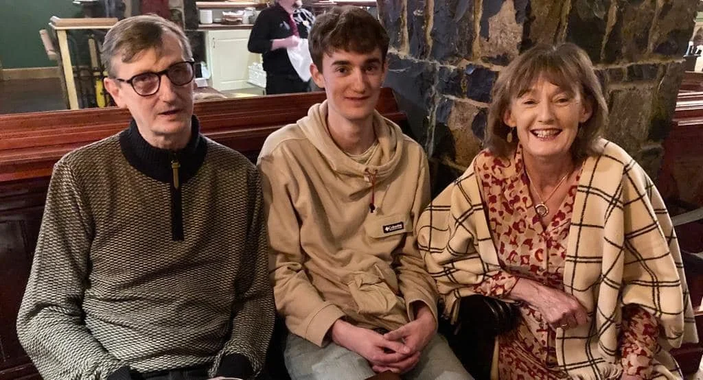 Breda, son and friend sitting at a restaurant table, smiling and posing for the photo.