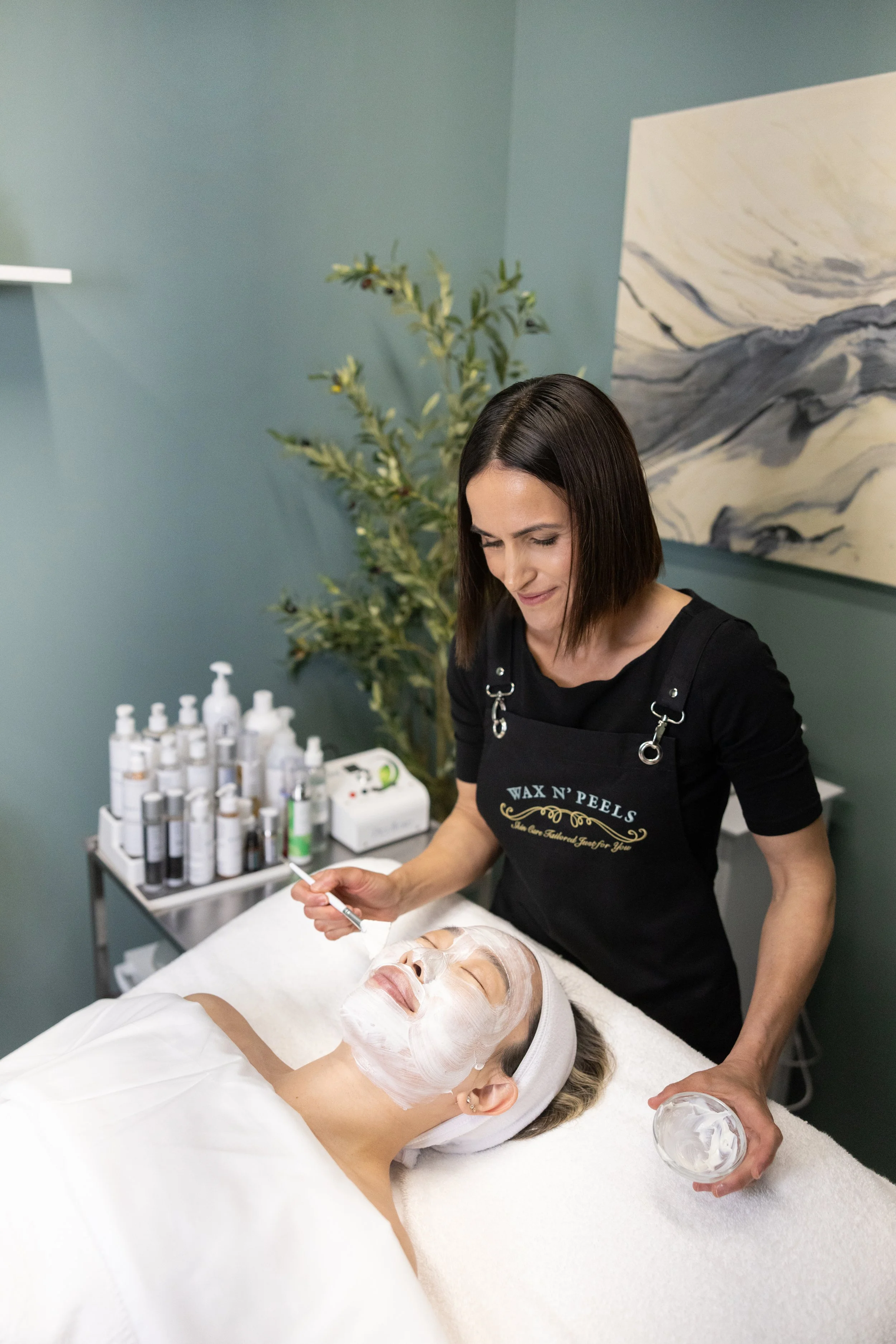 Perla performing a customized facial treatment at Wax n' Peels in Monrovia, CA using professional skincare products tailored to the client's skin needs.