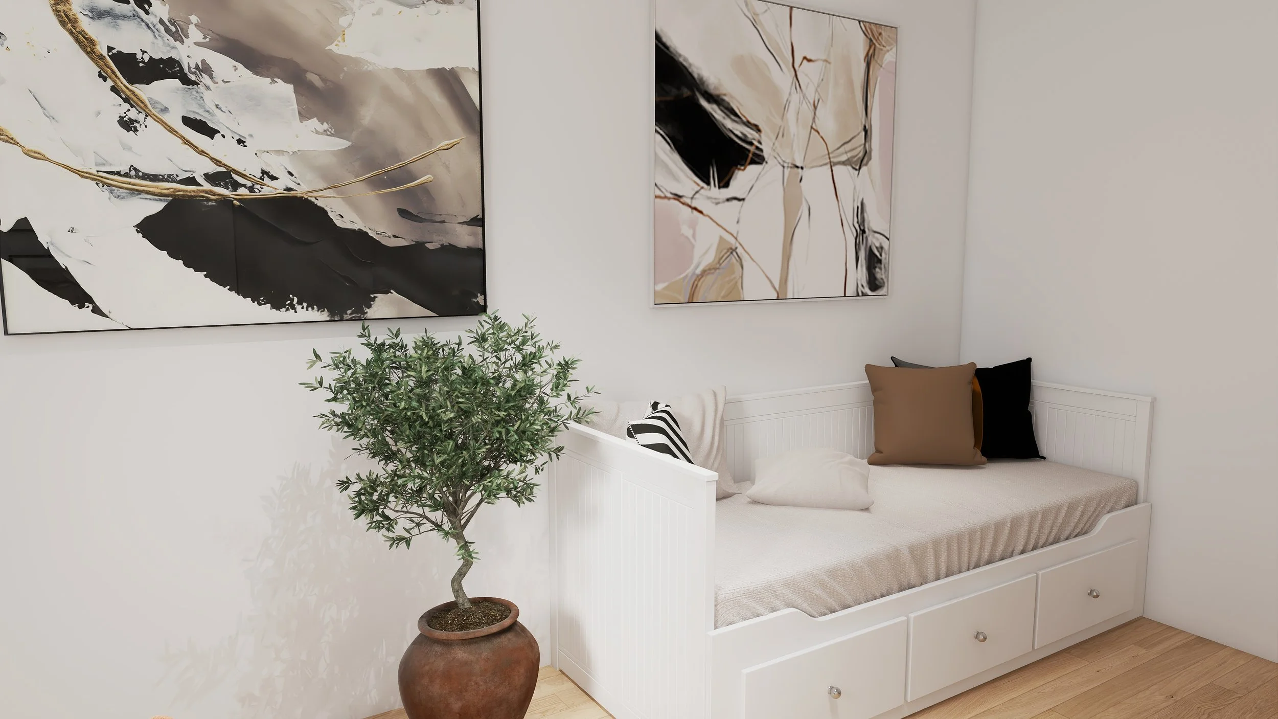 A cozy white daybed with three pillows in shades of black, brown, and cream, positioned against a white wall, with abstract black, beige, and white artwork hanging above. A potted small green tree in a brown ceramic pot is placed next to the daybed.