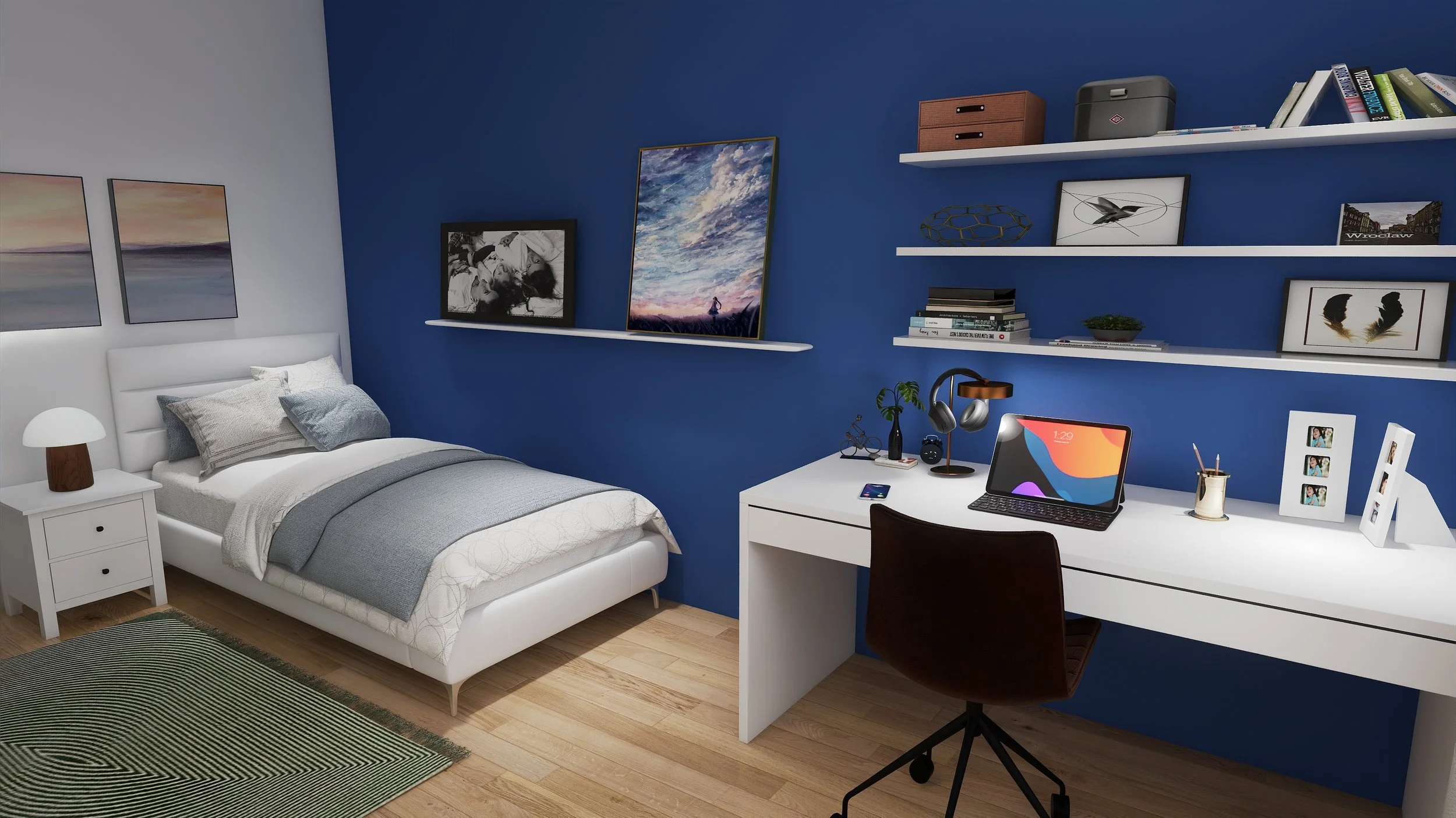 A bedroom with a white bed, gray and white bedding, white nightstand, and desk with a monitor and accessories. Blue and white walls with framed artwork and shelves holding books, décor, and photos. Wooden flooring with a green and black striped rug.