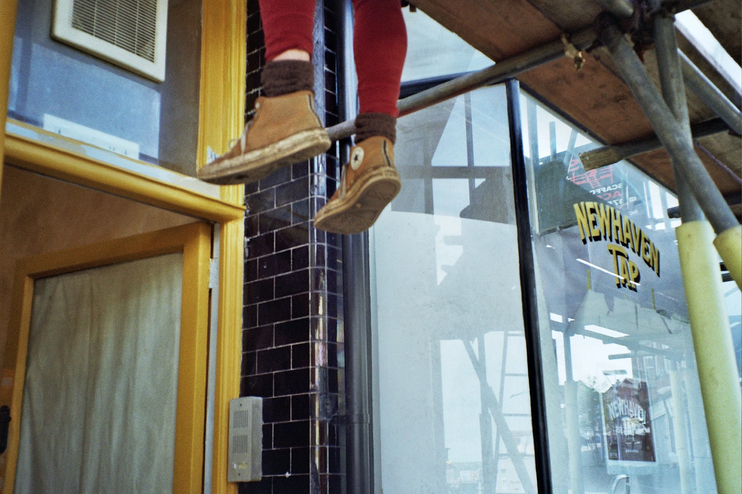 Dan from the marquee facade painting the sign with his legs dangling under the scaffolding