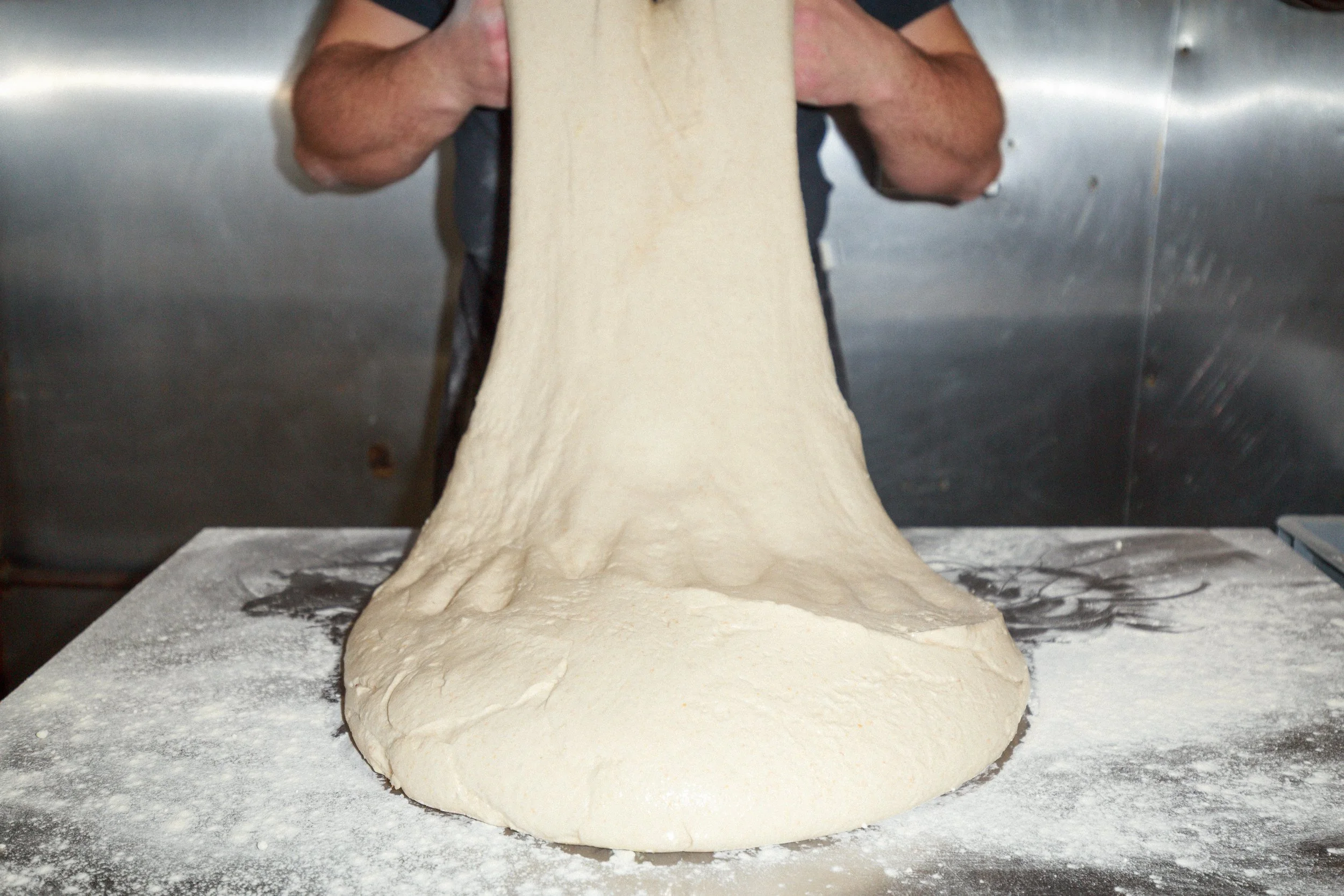 Dough being stretched and shaped by a baker.