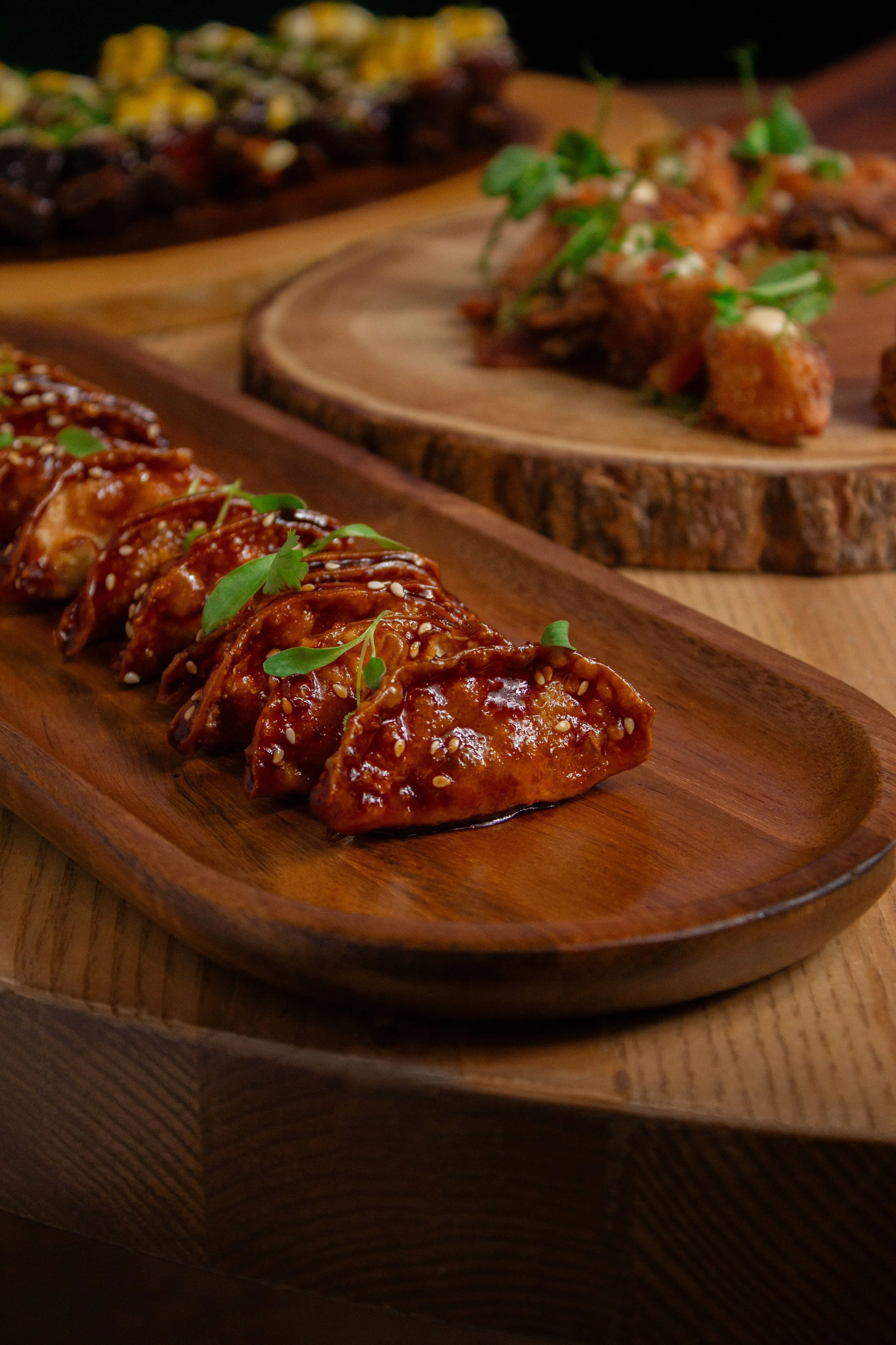 Close-up of glazed chicken wings garnished with fresh herbs on a wooden serving platter