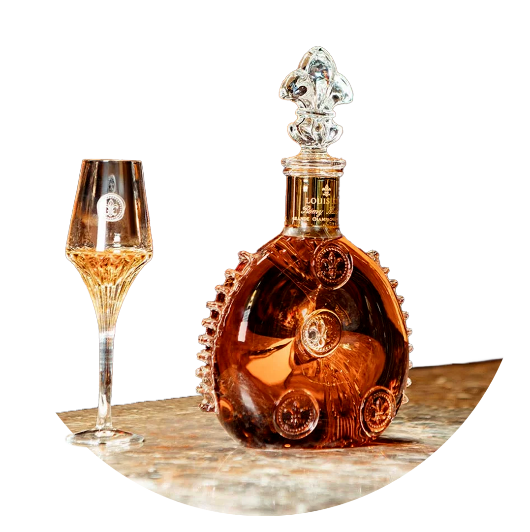 A decorative bottle of Louis Roederer champagne with a matching champagne flute on a wooden surface against a black background.