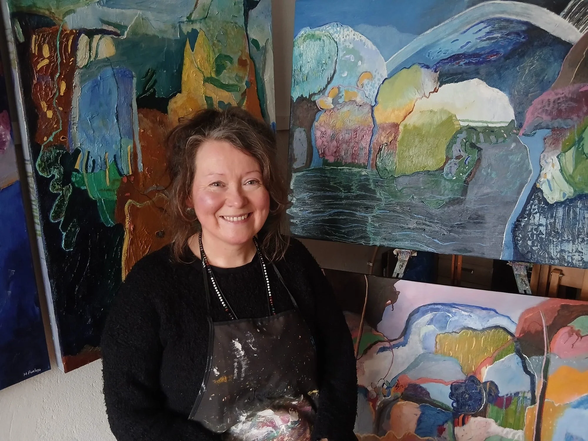 Irish artist Martina Furlong in the studio beside her abstract landscape oil paintings