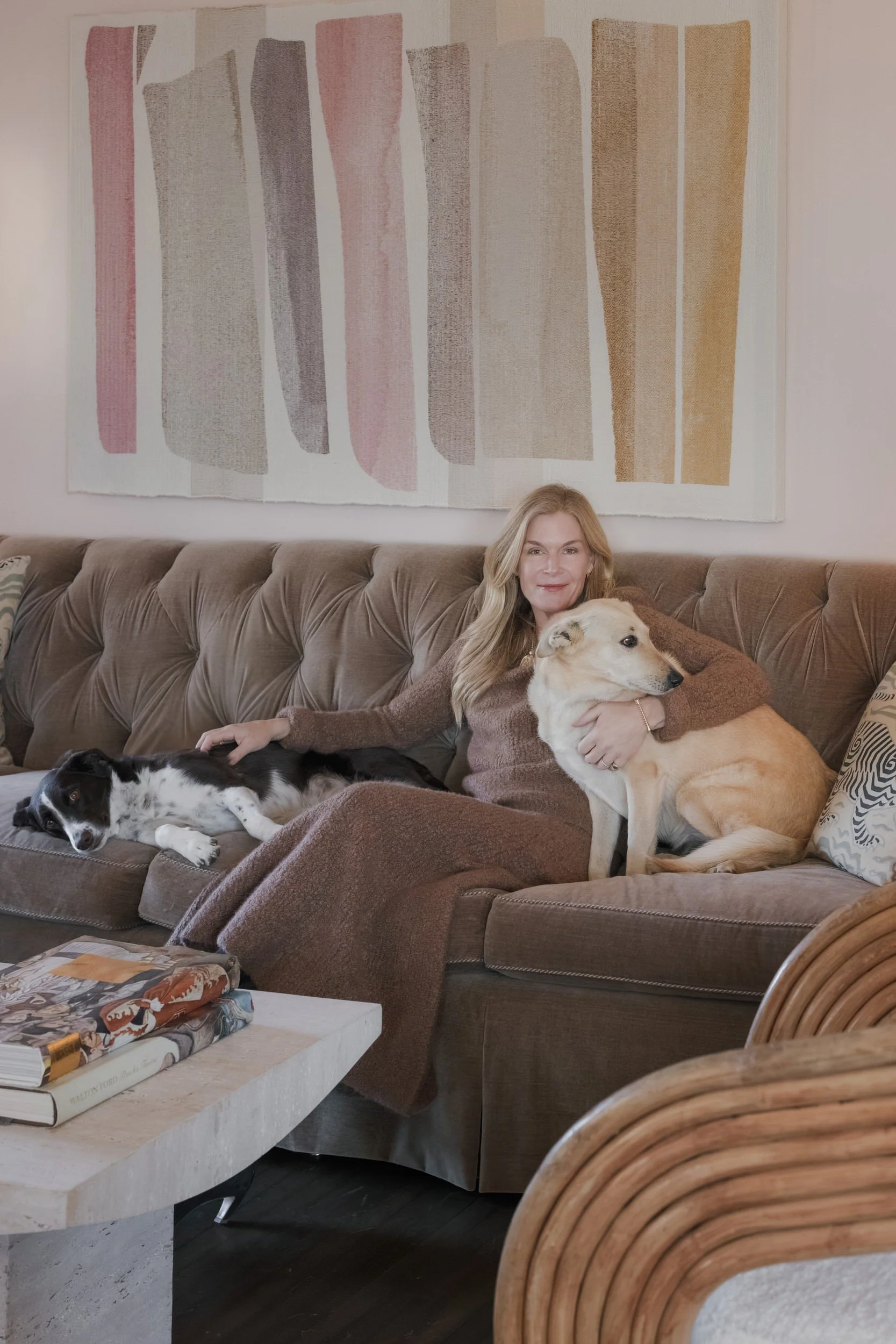 Cecilia Wolfson relaxing at home on a velvet sofa beneath a contemporary watercolor painting
