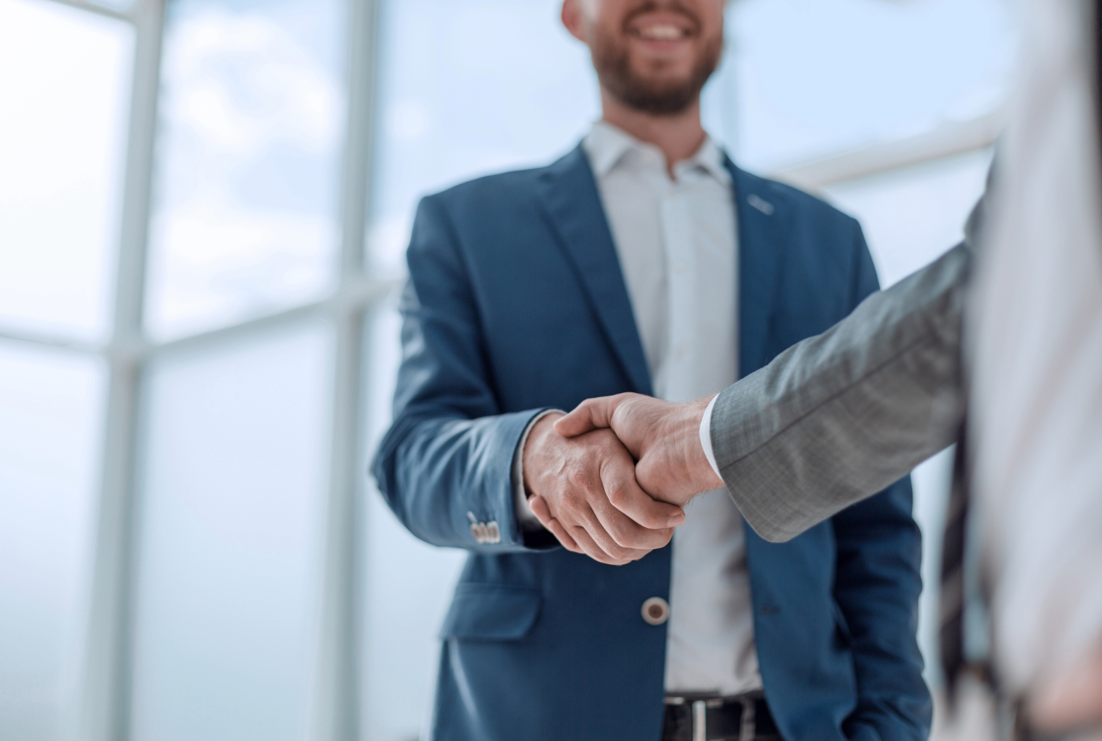 Two men in business suits shaking hands in an office.