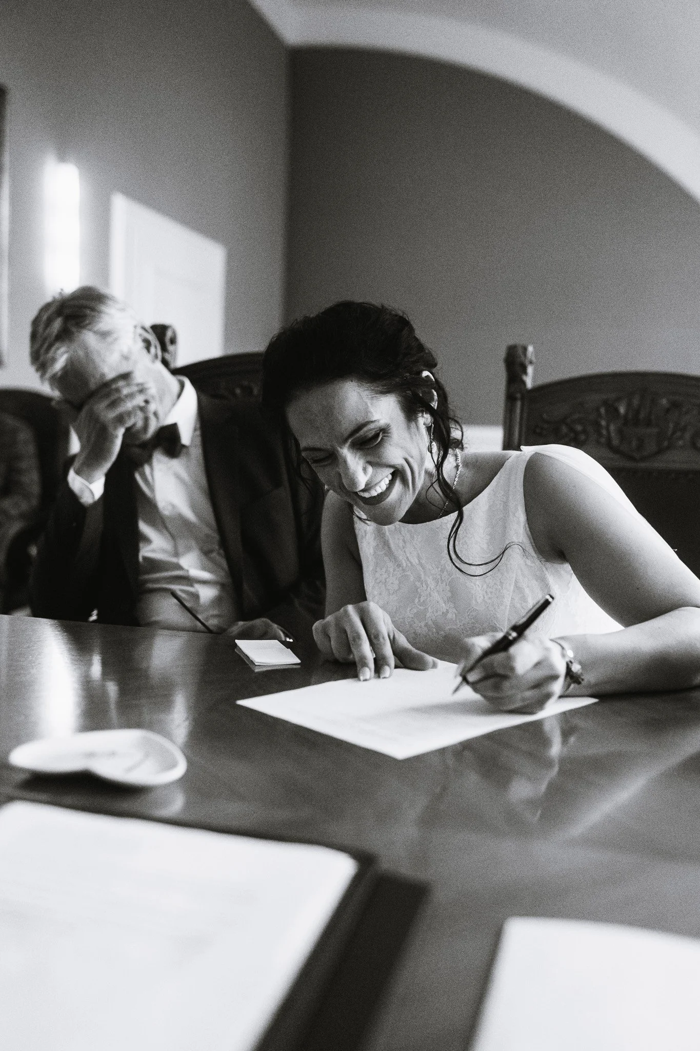A candid portrait of a couple signing their marriage certificate, photographed by Cécile : Fine-art wedding photography in Provence, Paris, and luxury destination locations