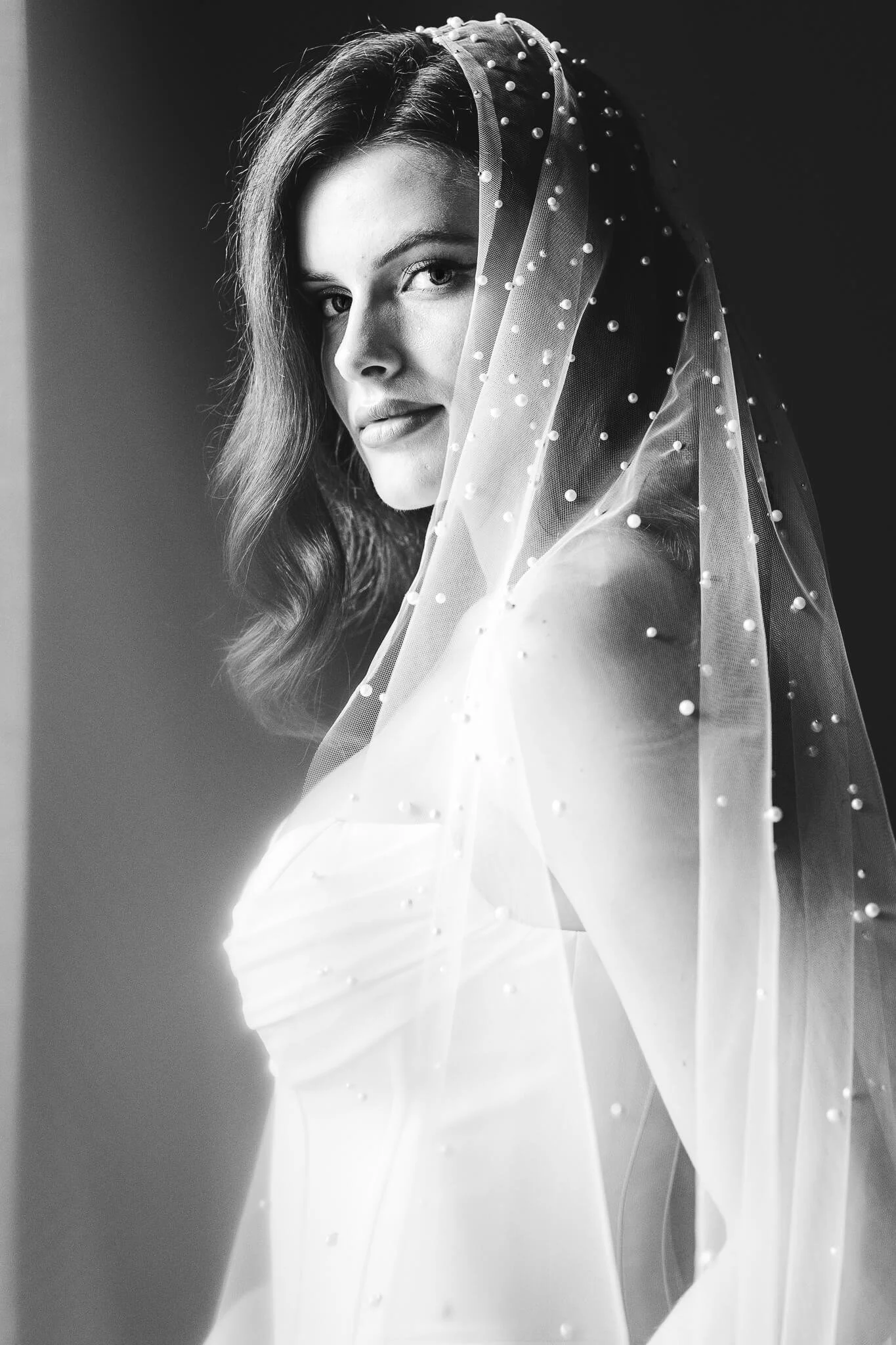 A luxurious black-and-white portrait of a bride wearing a high-end pearl veil. Fine-art wedding photography by Cécile Wedding, Provence, Paris, and destination