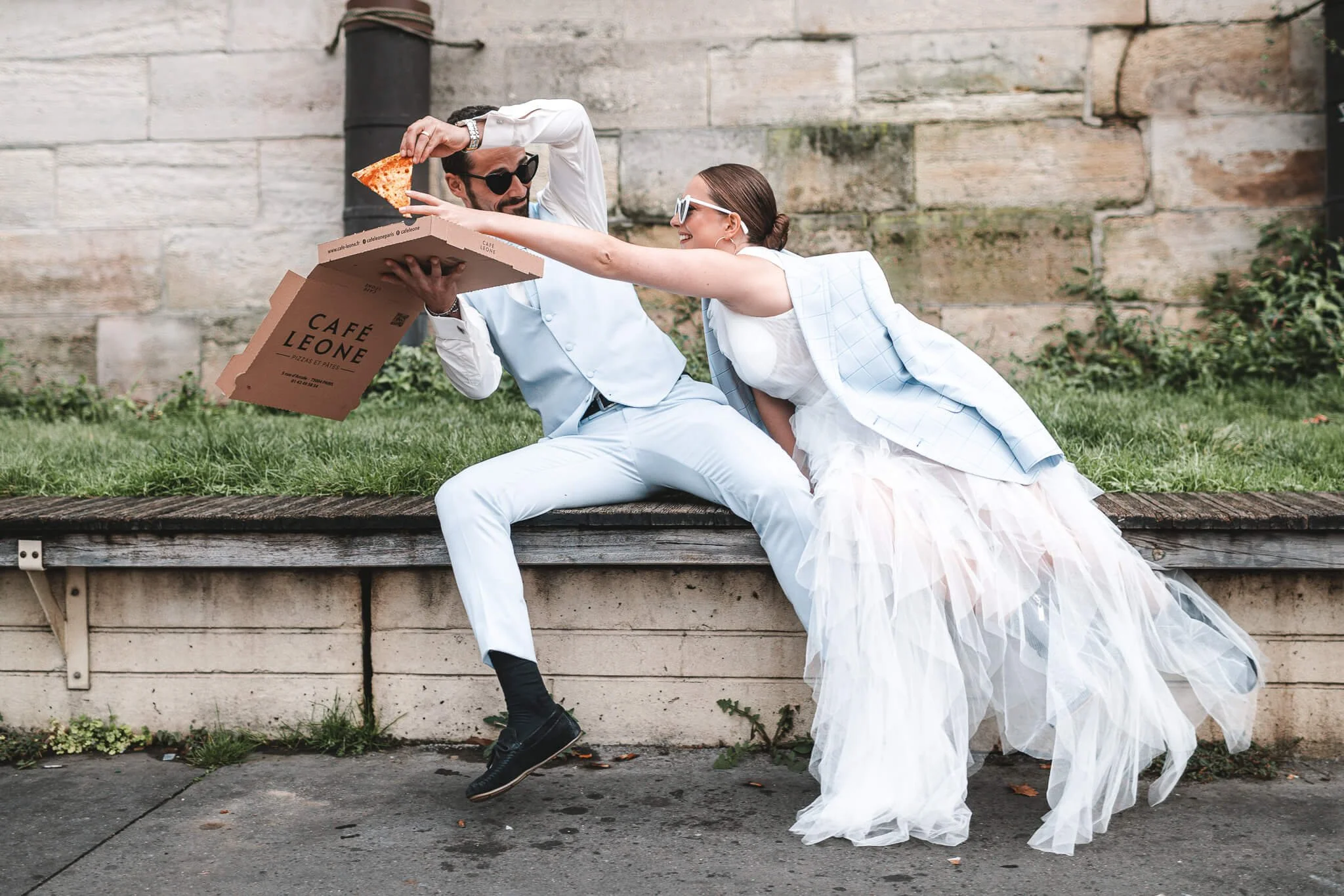 Candid photo of a newlywed couple arguing over a slice of pizza on the streets of Paris, by fine-art wedding photographer Cécile Wedding, Provence and destination