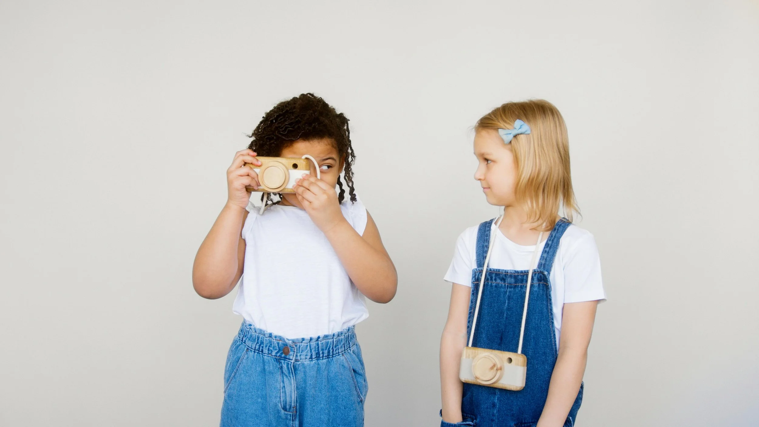 two girls playing with wooden camera