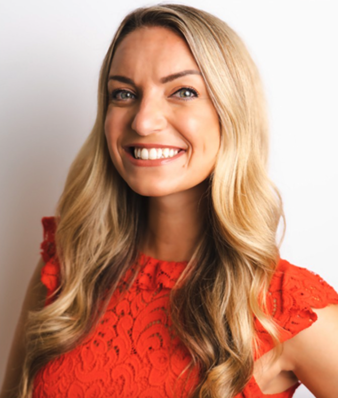 Woman with long blonde hair wearing a red lace dress smiling at the camera.