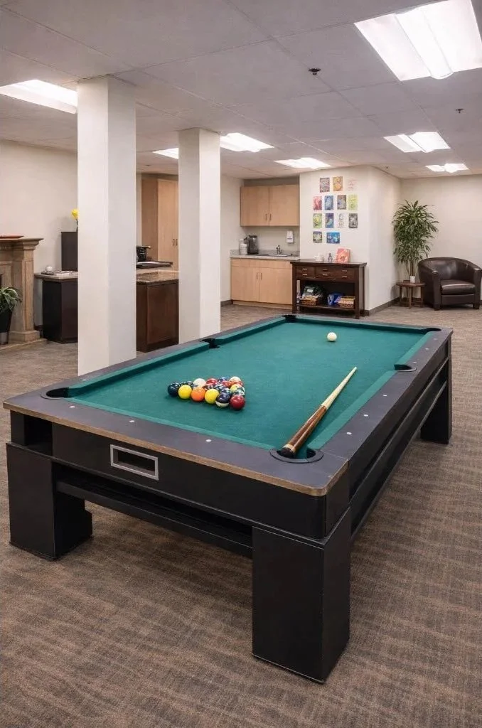 Indoor recreational room with a pool table, cue stick, and arranged pool balls, featuring neutral walls, ceiling, and carpeted floor.