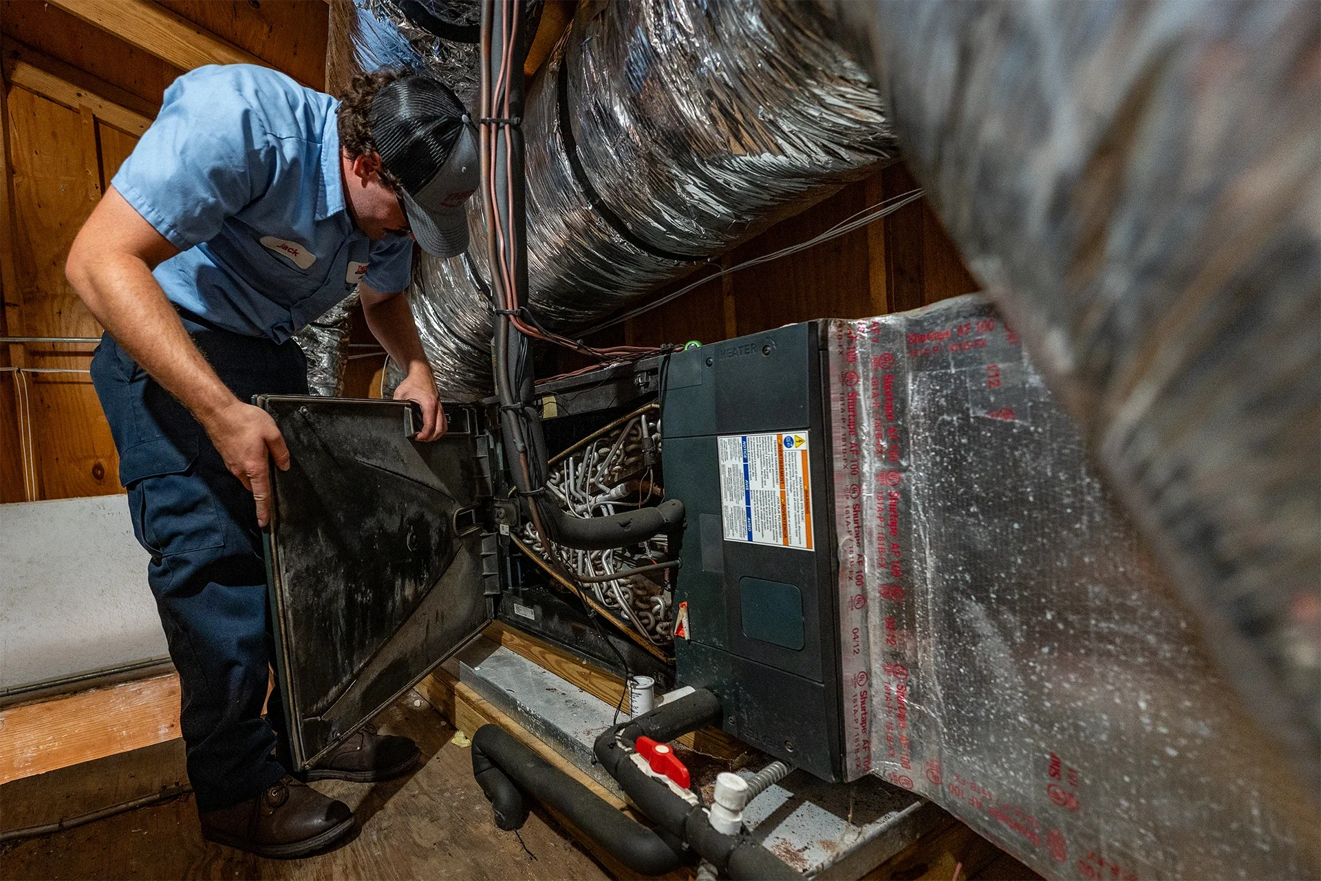 man removing front panel of a residential air duct