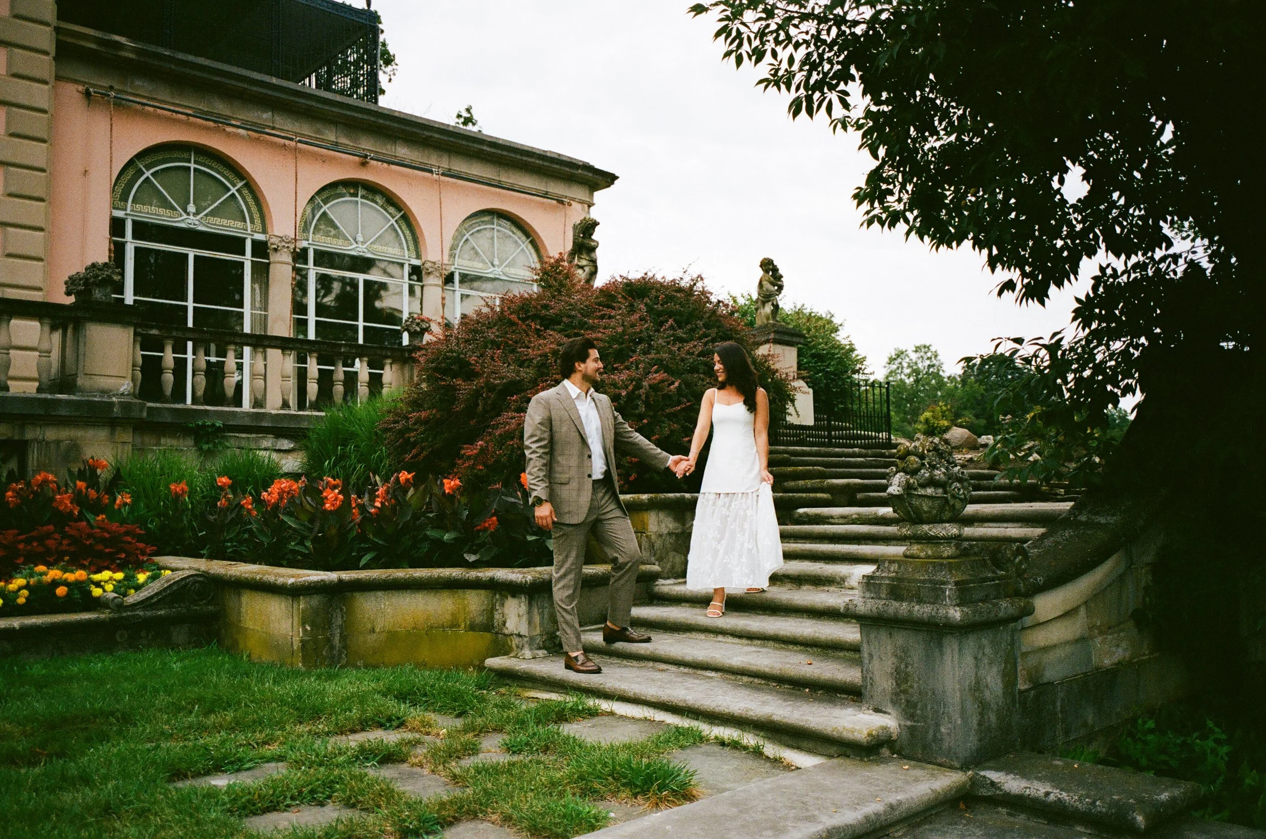 Fine art film engagement portrait of a couple walking hand in hand at Cuneo Mansion courtyard.