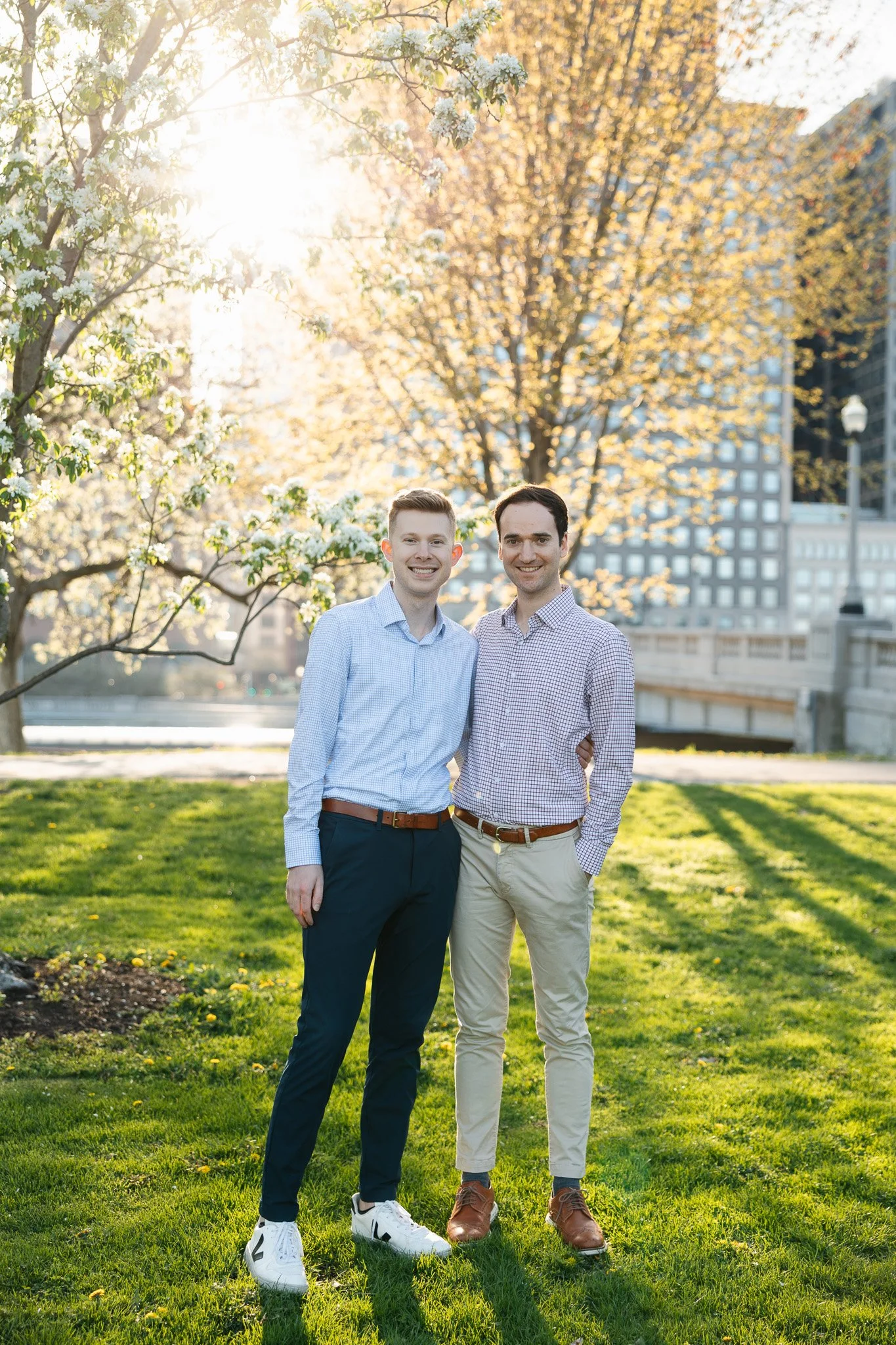 lgbtq couple in the park for engagement photos with sunset and flowers