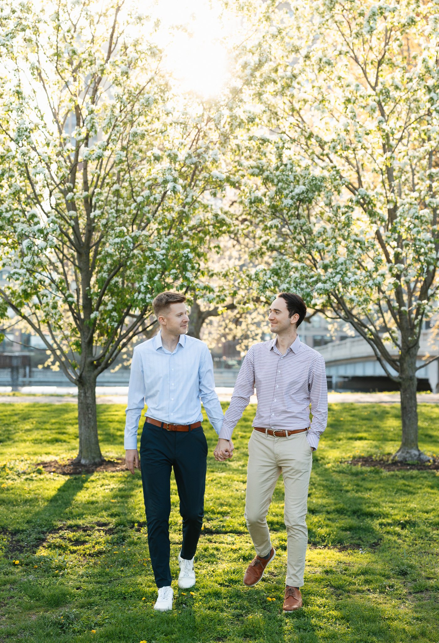 lgbtq couple in the park for engagement photos with sunset and flowers