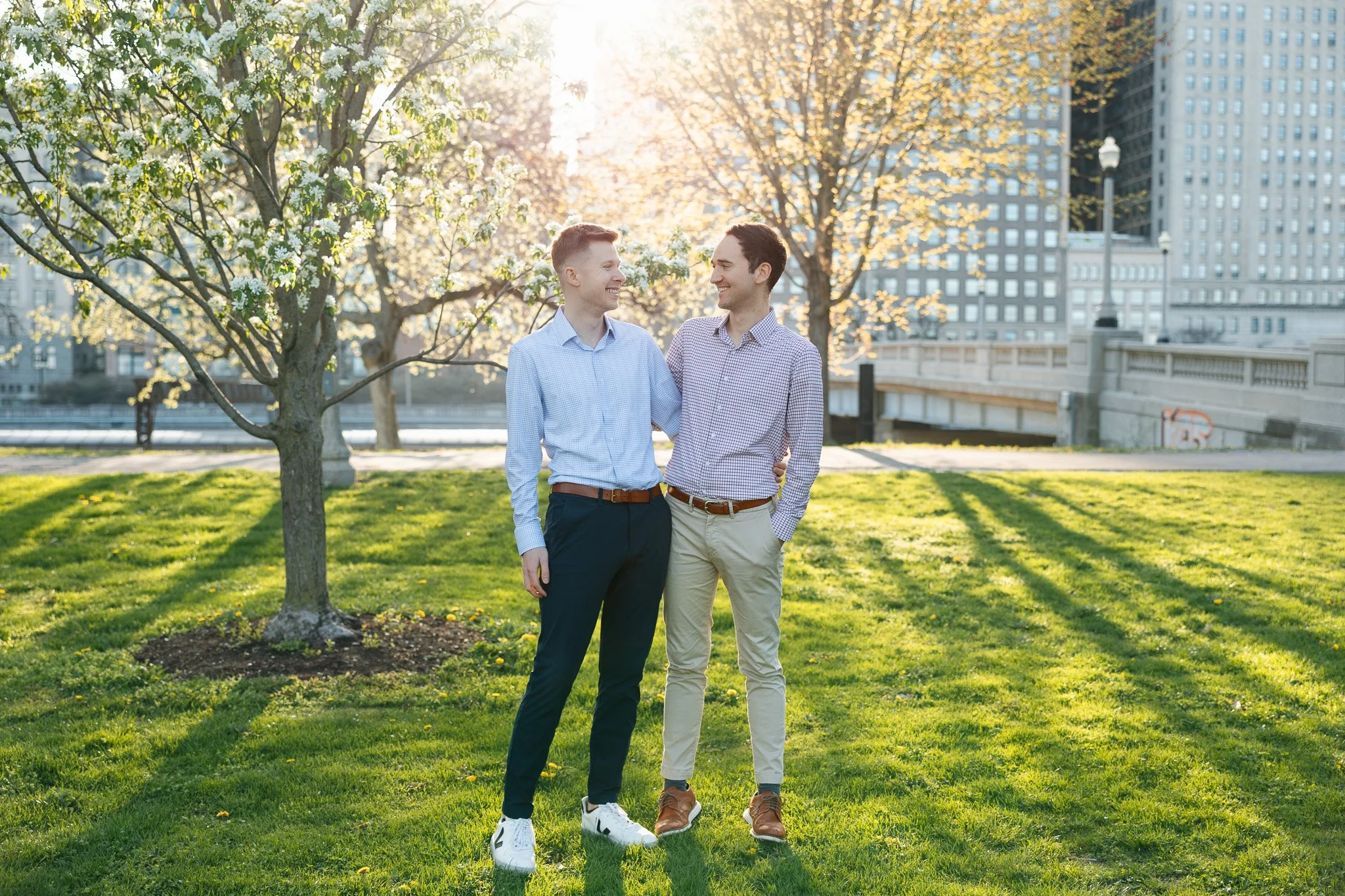 lgbtq couple in the park for engagement photos with sunset and flowers