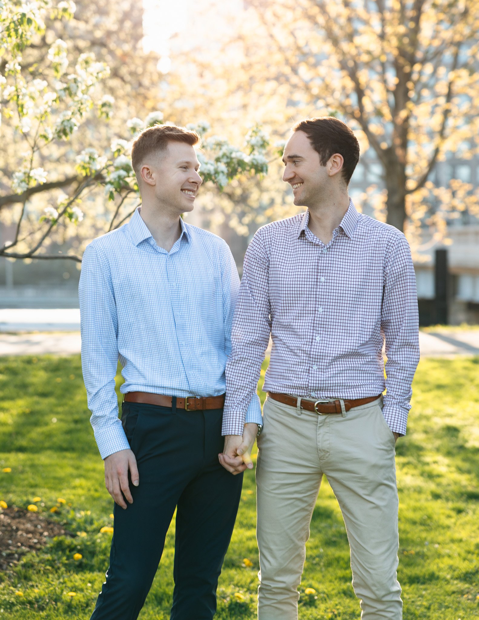 lgbtq couple in the park for engagement photos with sunset and flowers