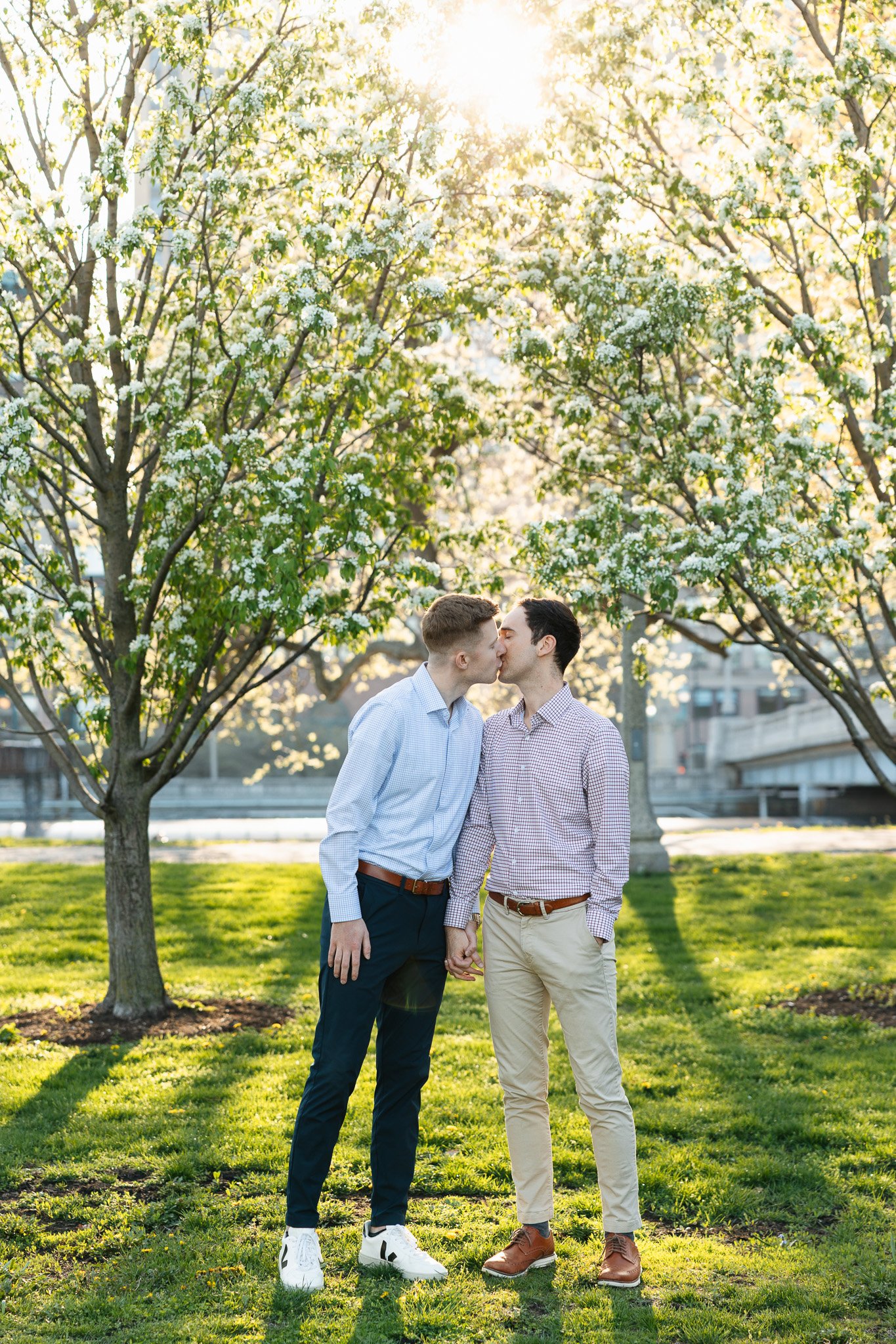 lgbtq couple in the park for engagement photos with sunset and flowers
