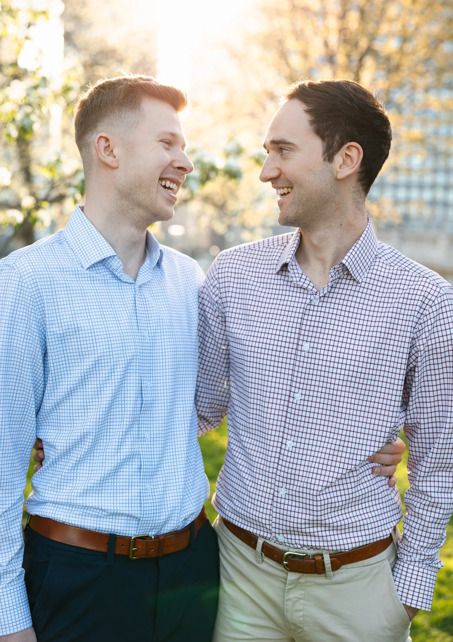 lgbtq couple in the park for engagement photos with sunset and flowers