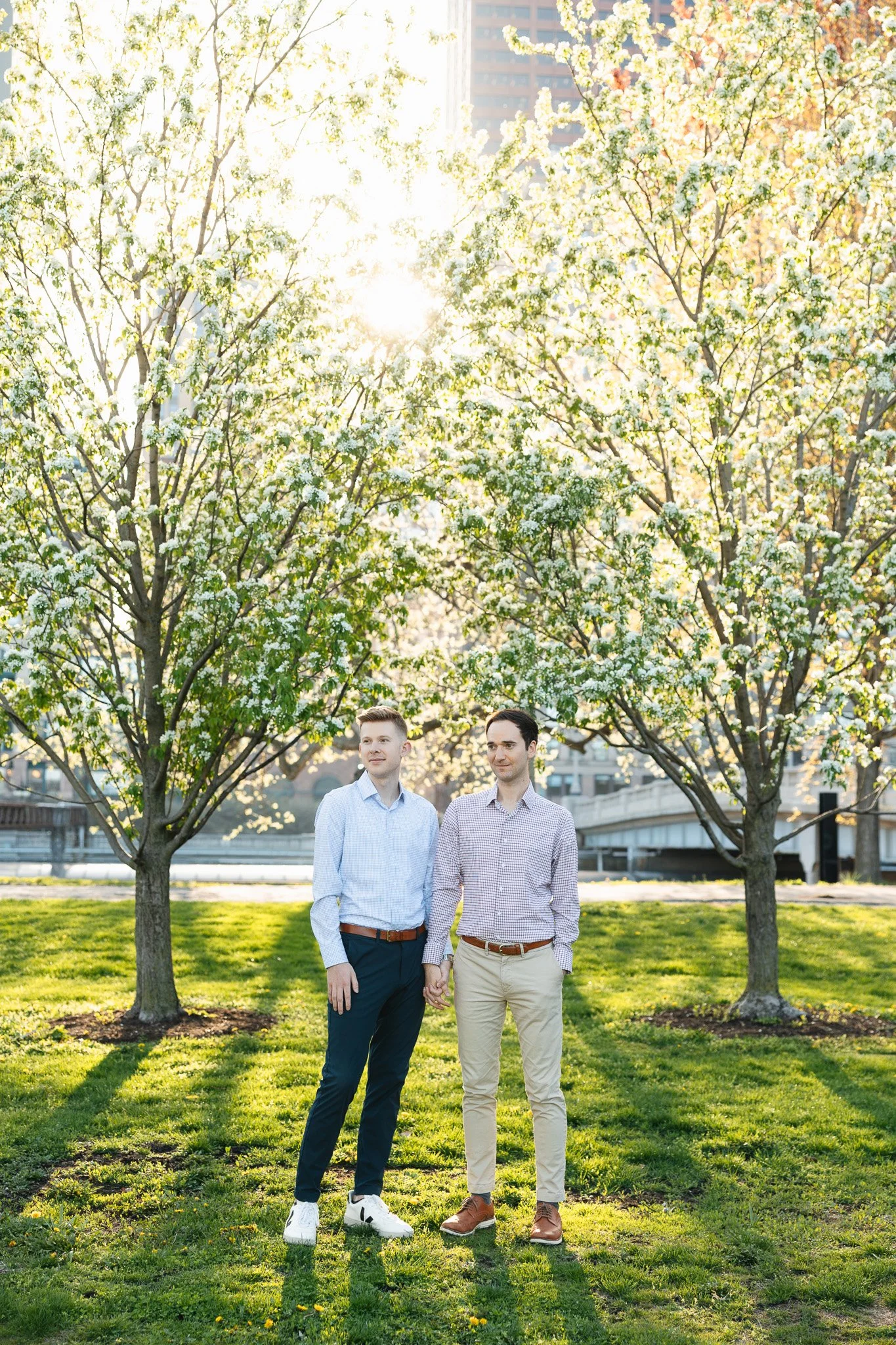 lgbtq couple in the park for engagement photos with sunset and flowers