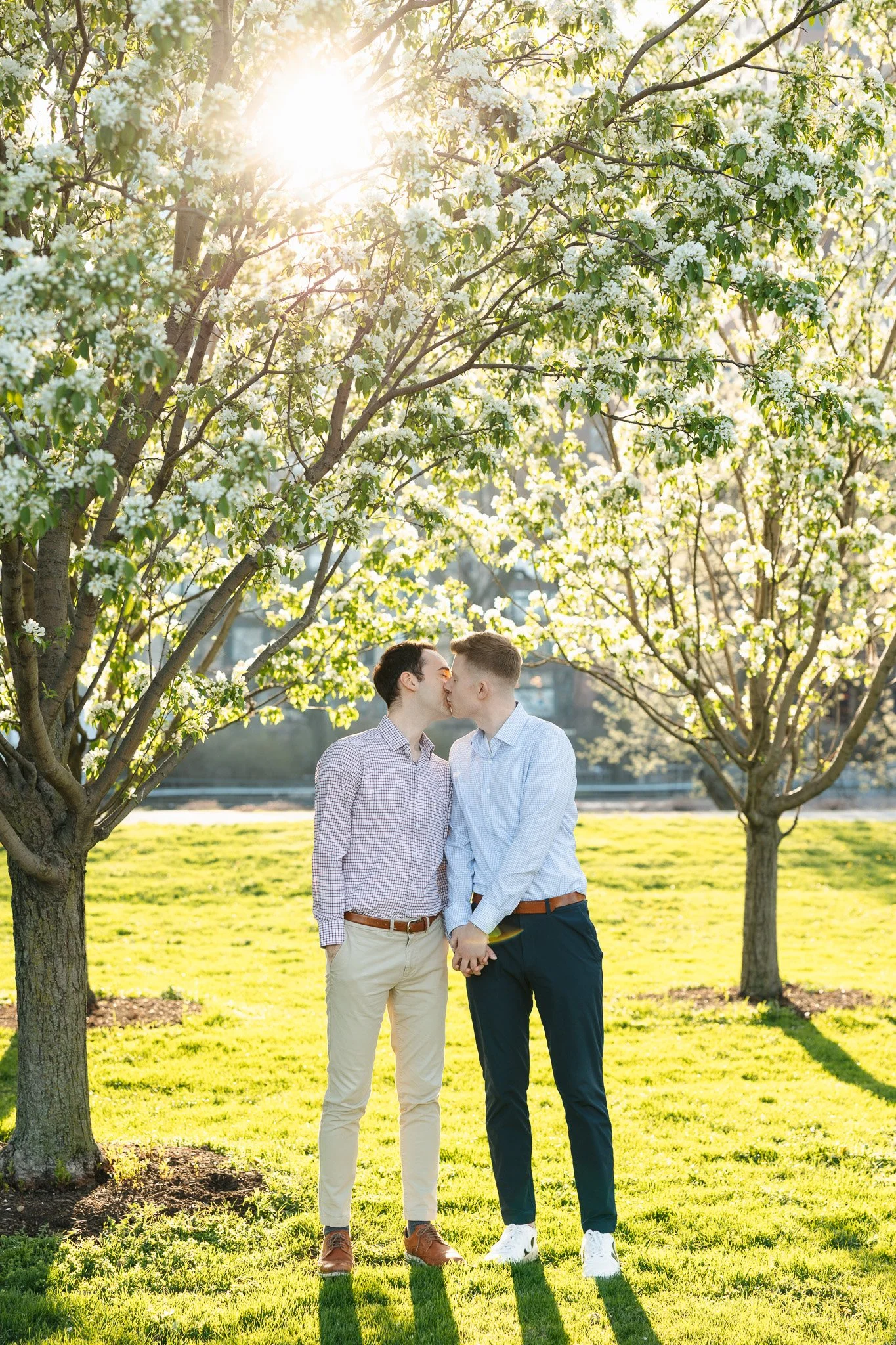 lgbtq couple in the park for engagement photos with sunset and flowers