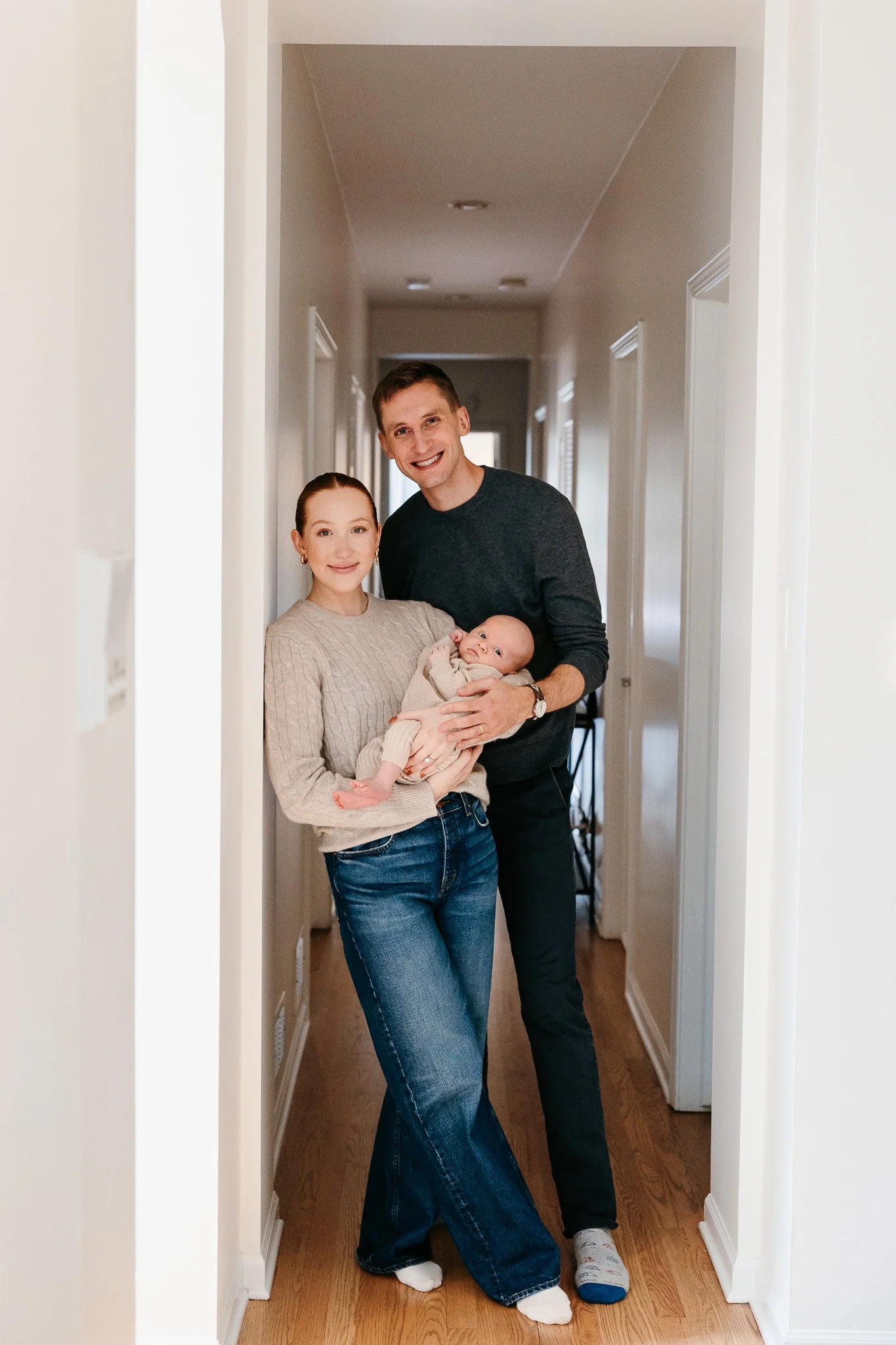 parents holding newborn baby for newborn photos in the hallway at home