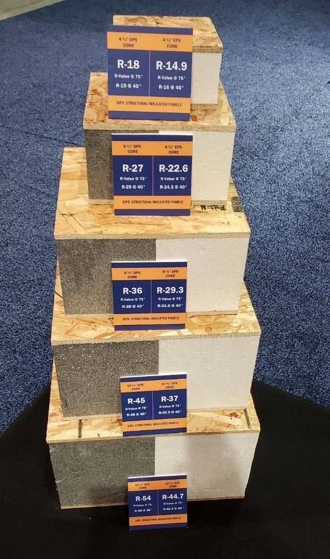 Display of structural insulated panels with labels showing different R-values, core types, and insulation specifications, arranged on wooden stands.