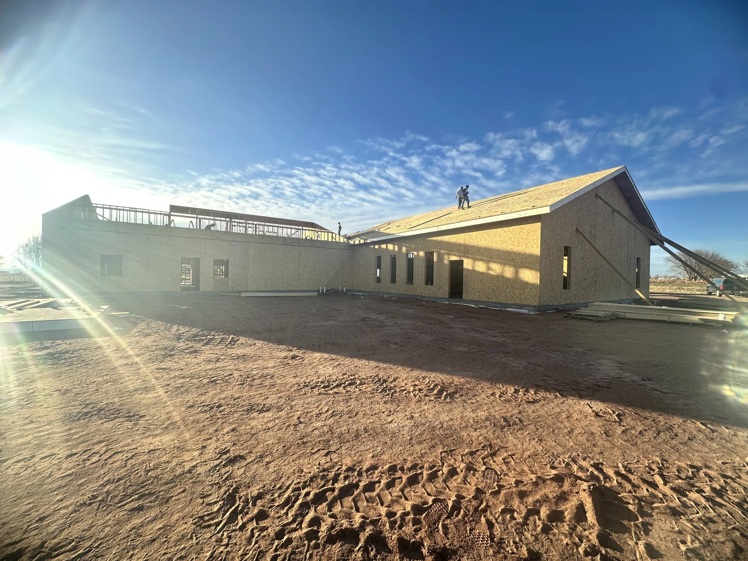 Structural Insulated Panel roof installation with workers assembling SIP roof and wall panels on a building