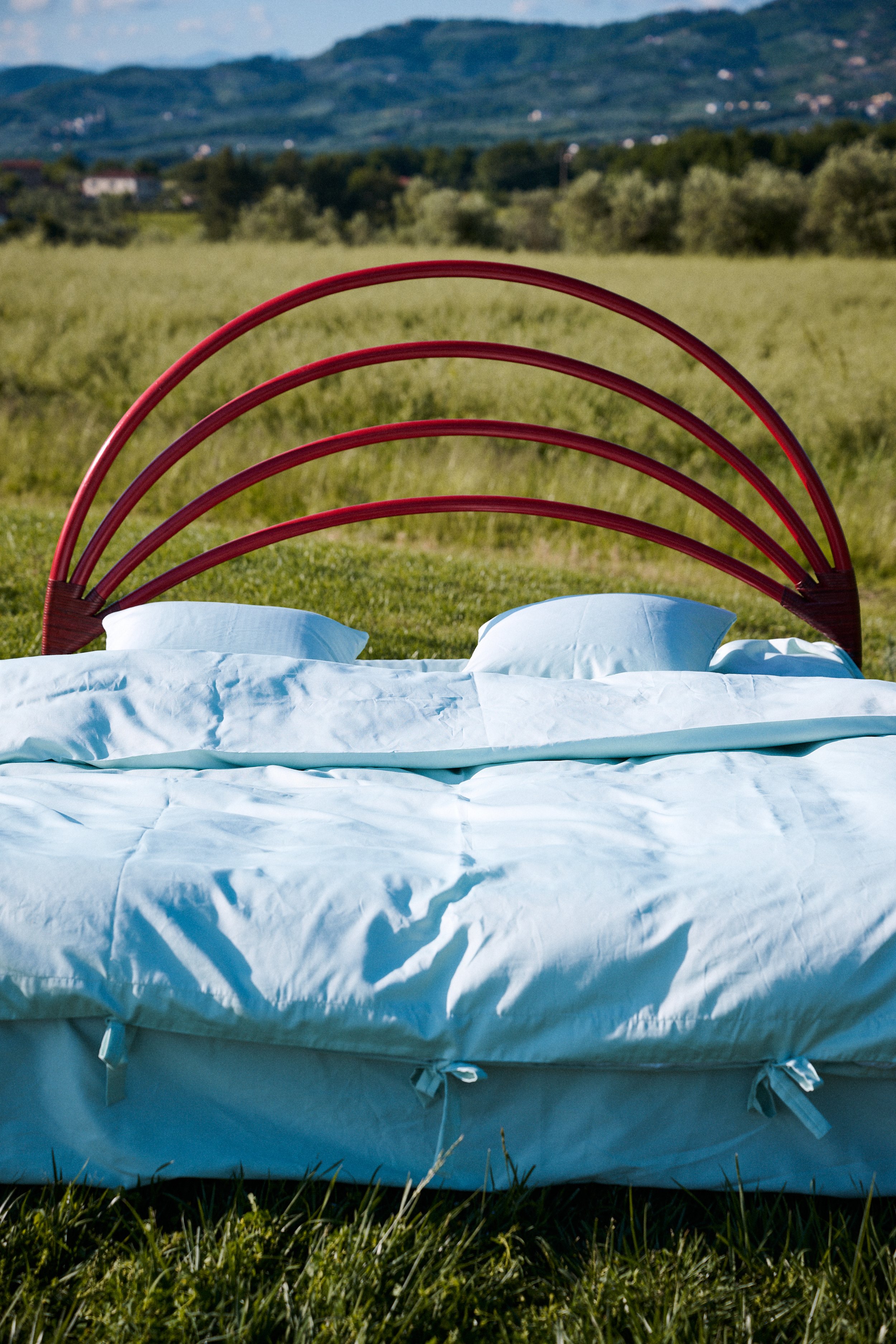 Vintage sculptural red bamboo bedframe curated in Tuscany by Yvonne Koné.