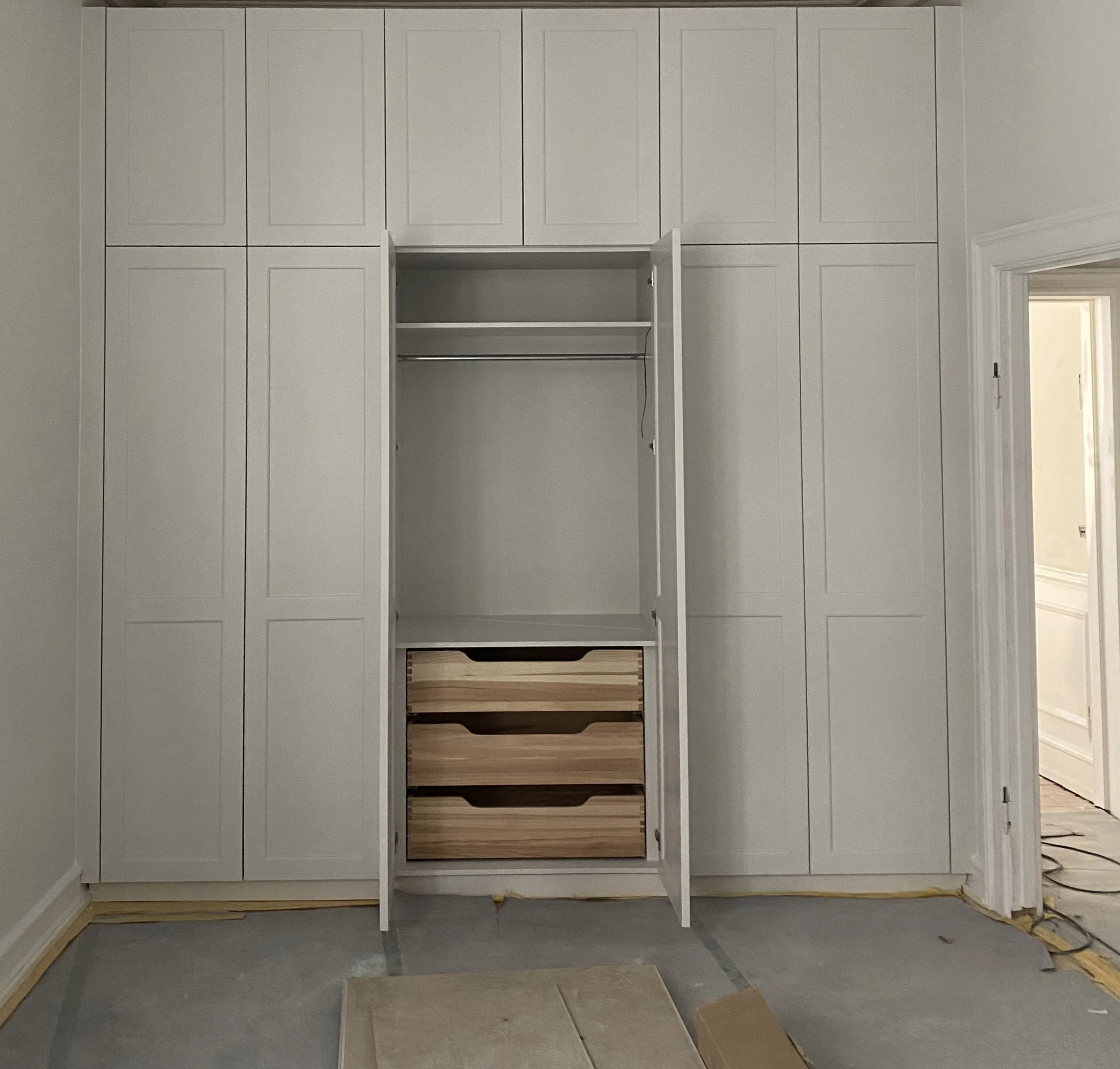 Handpainted custom wardrobe with solid wood drawers and light gray cabinetry designed by Yvonne Koné.