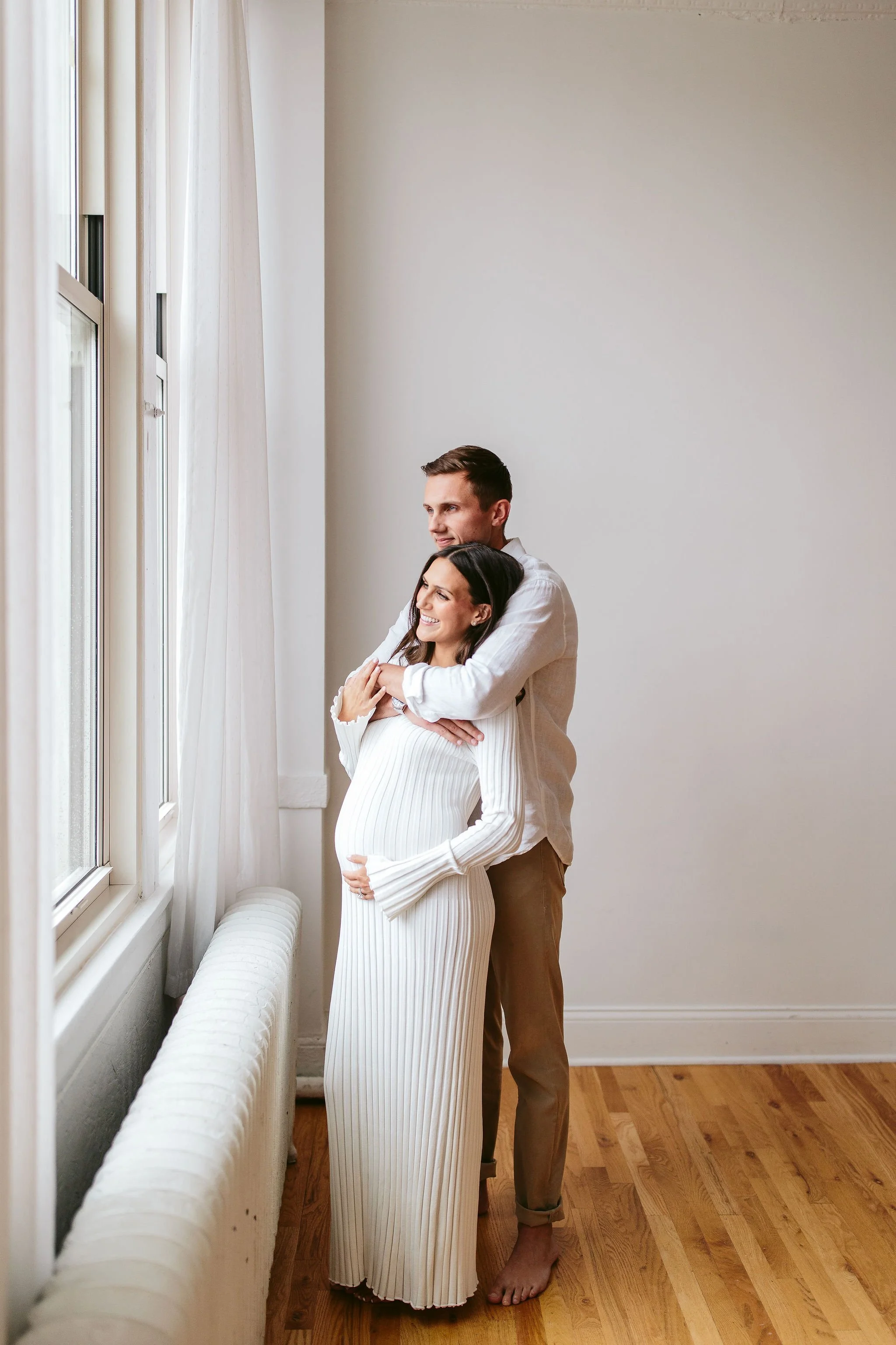 Couple looking out the window during maternity photos
