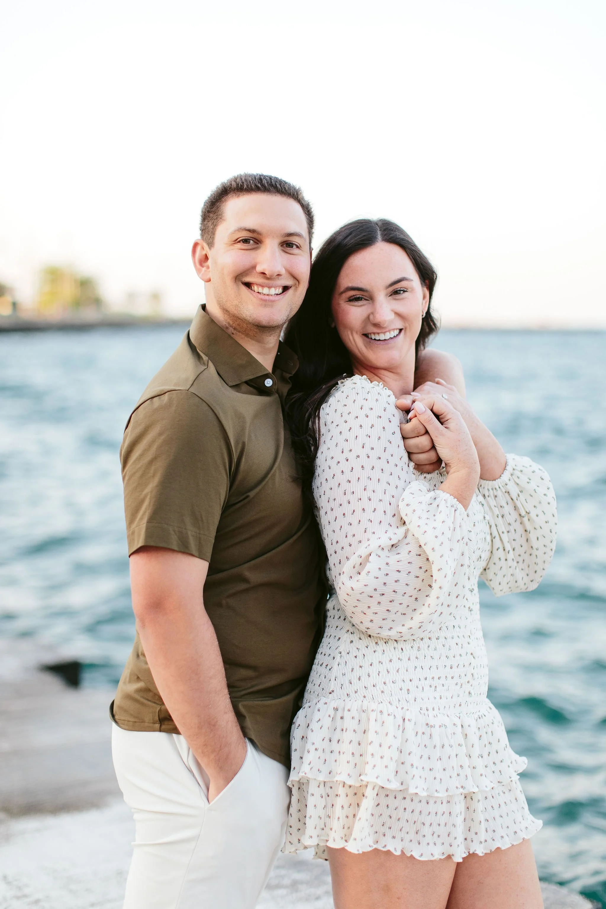Young couple smiling at the camera in front of Lake Michigan