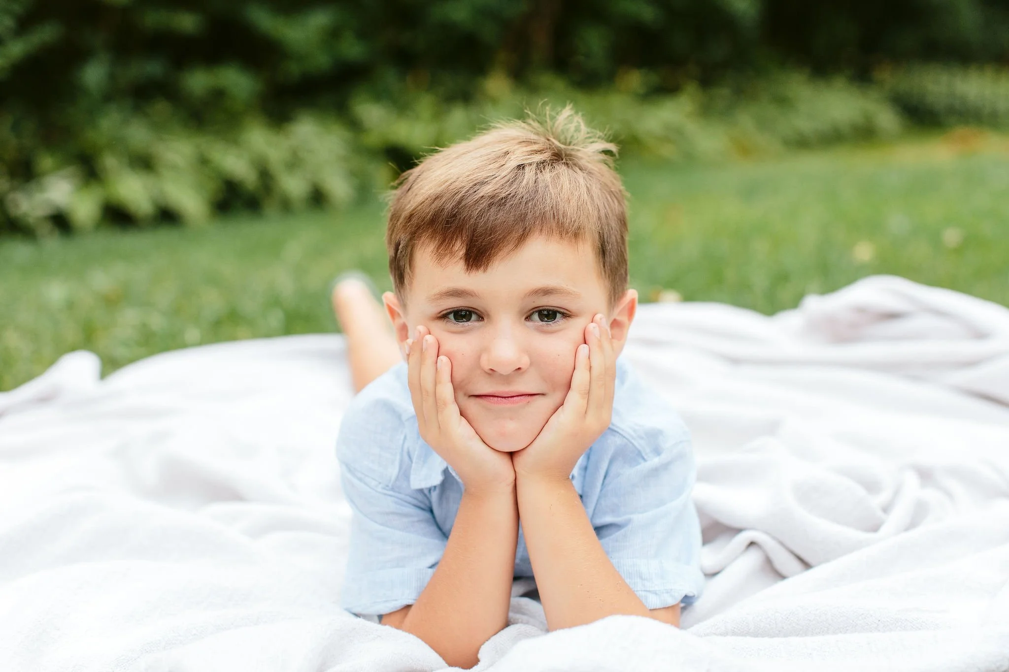 young boy laying on blanket in grass during chicago family session