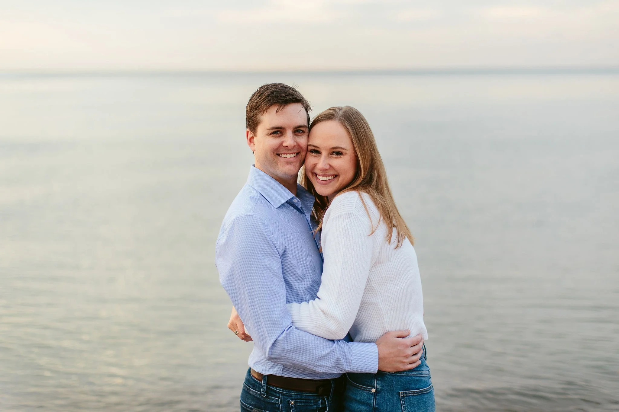 engaged couple smile for engagement photos in front of lake michigan