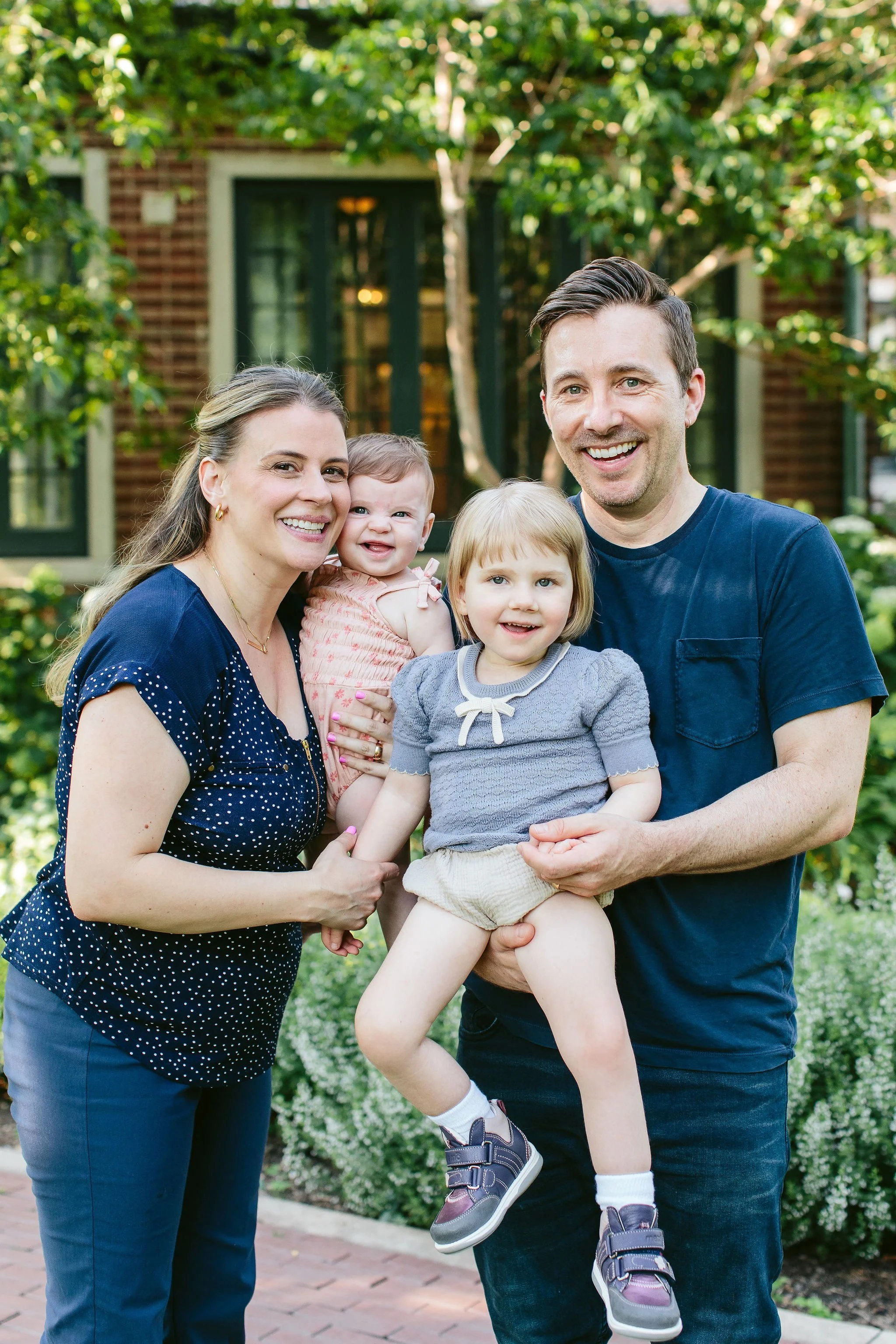 a young mom and dad pose with their two young girls during family photos