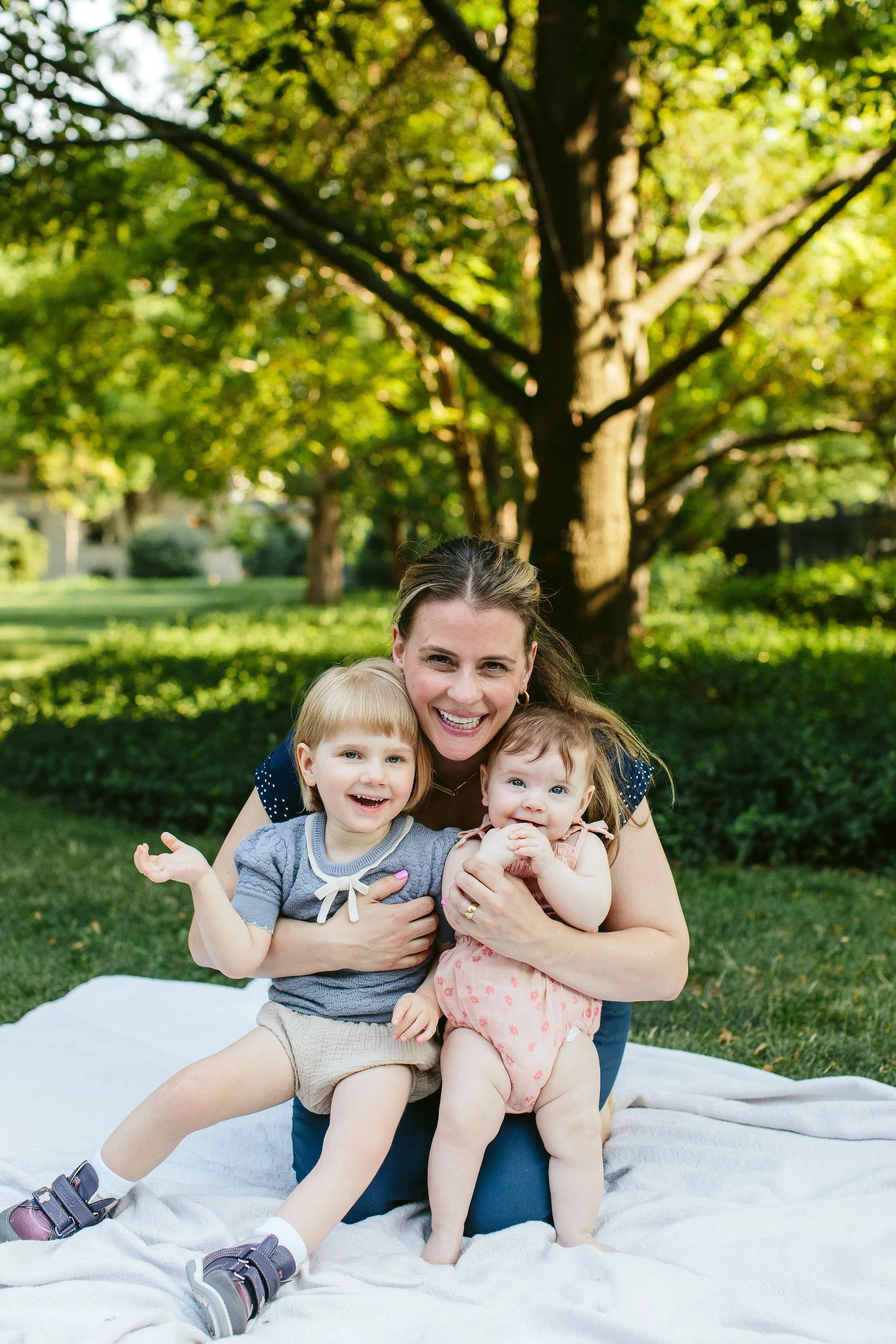 A mom gives her two young girls a hug and smiles 