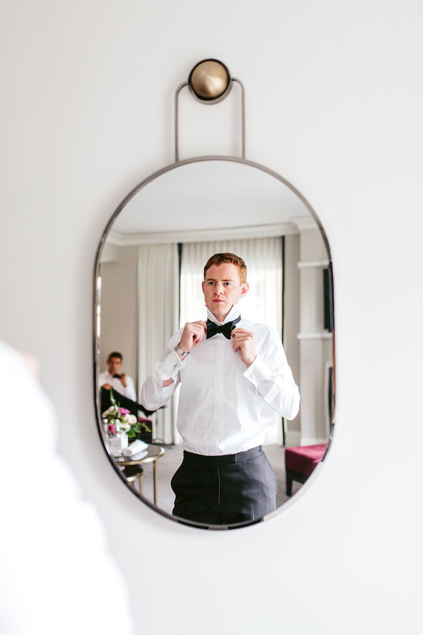 groom straightening bowtie in mirror