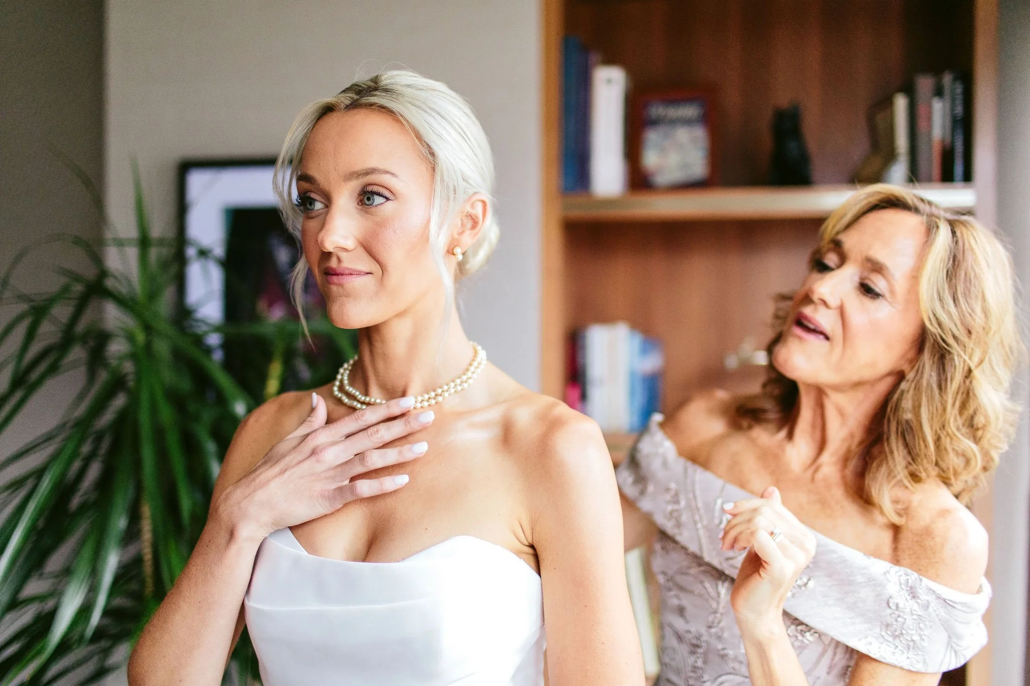 mom putting necklace on bride