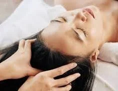 Woman receiving a head massage while lying down with eyes closed
