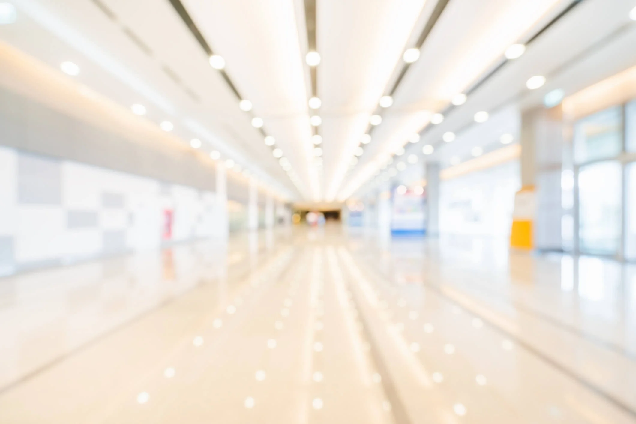 blurred, unfocused photo of an indoor retail mall or convention center with bright lights