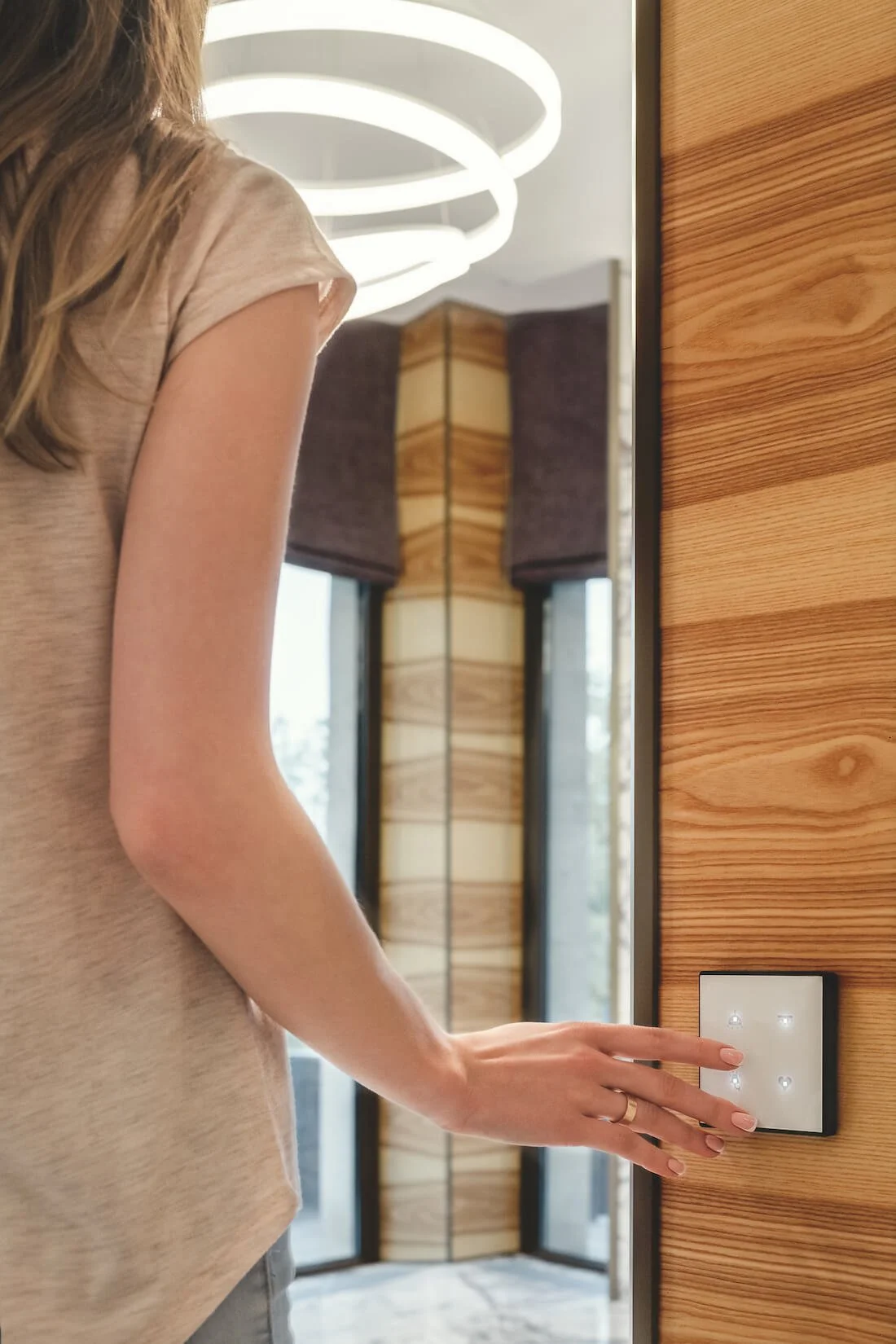 woman turning on an architectural lighting fixture with a touchscreen wall switch
