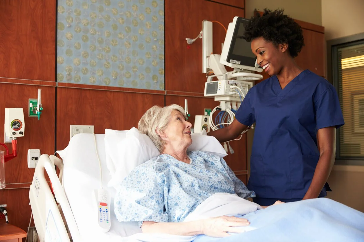 happy senior woman in a hospital bed talking to a smiling nurse