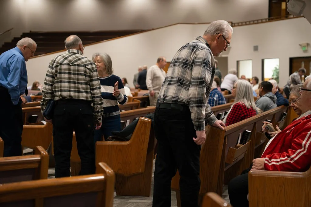 People sitting and chatting in a church pews during a service or gathering.